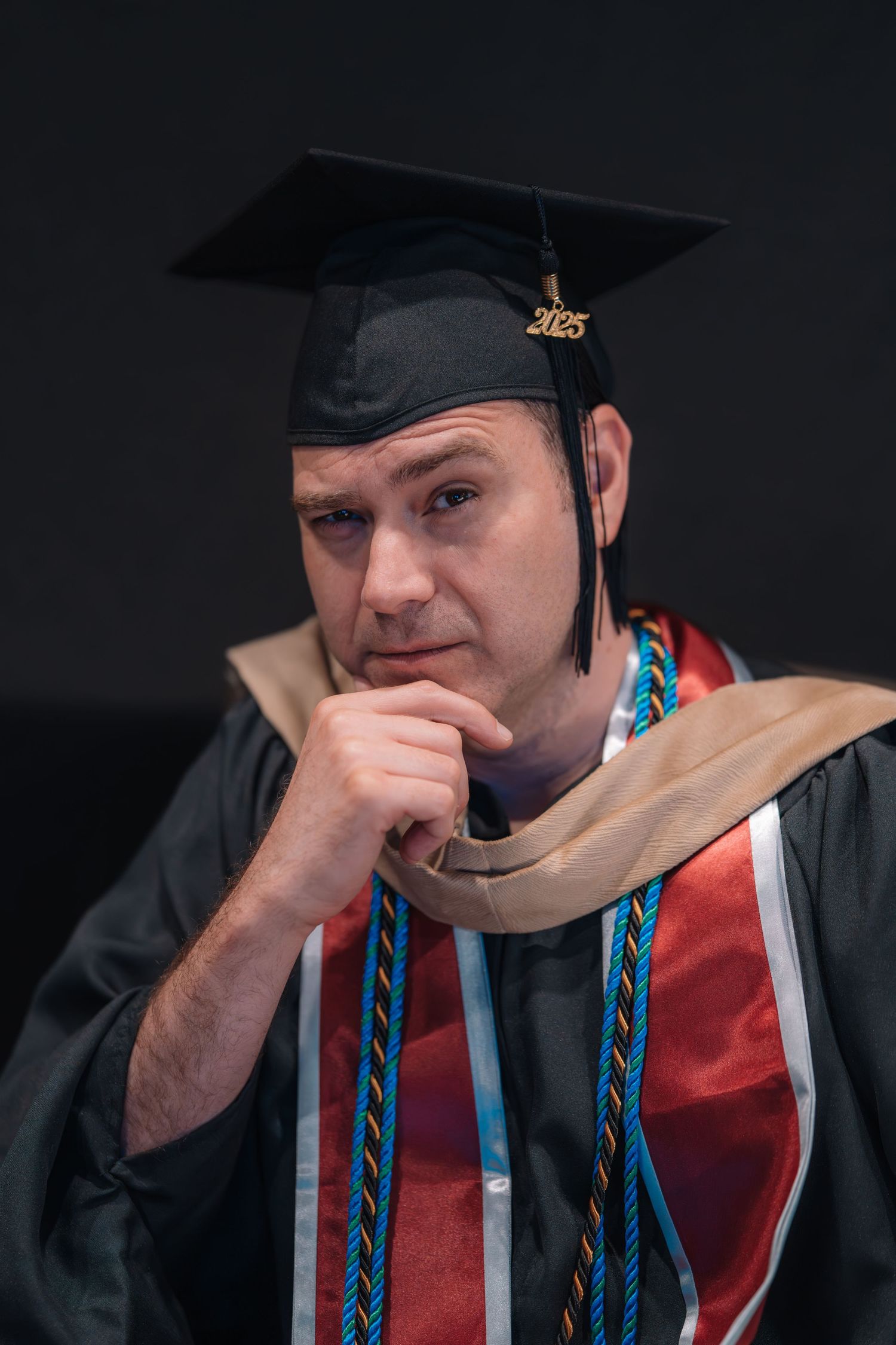 Graduate in black cap and gown with burgundy stole shown in progressive thoughtful poses.