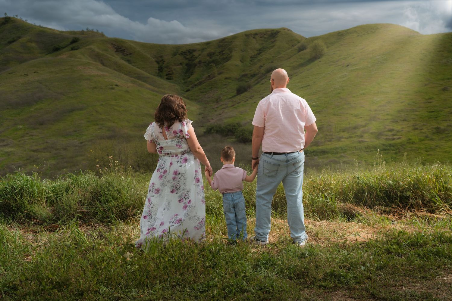 Family enjoying a scenic walk together on rolling green hills during sunset.