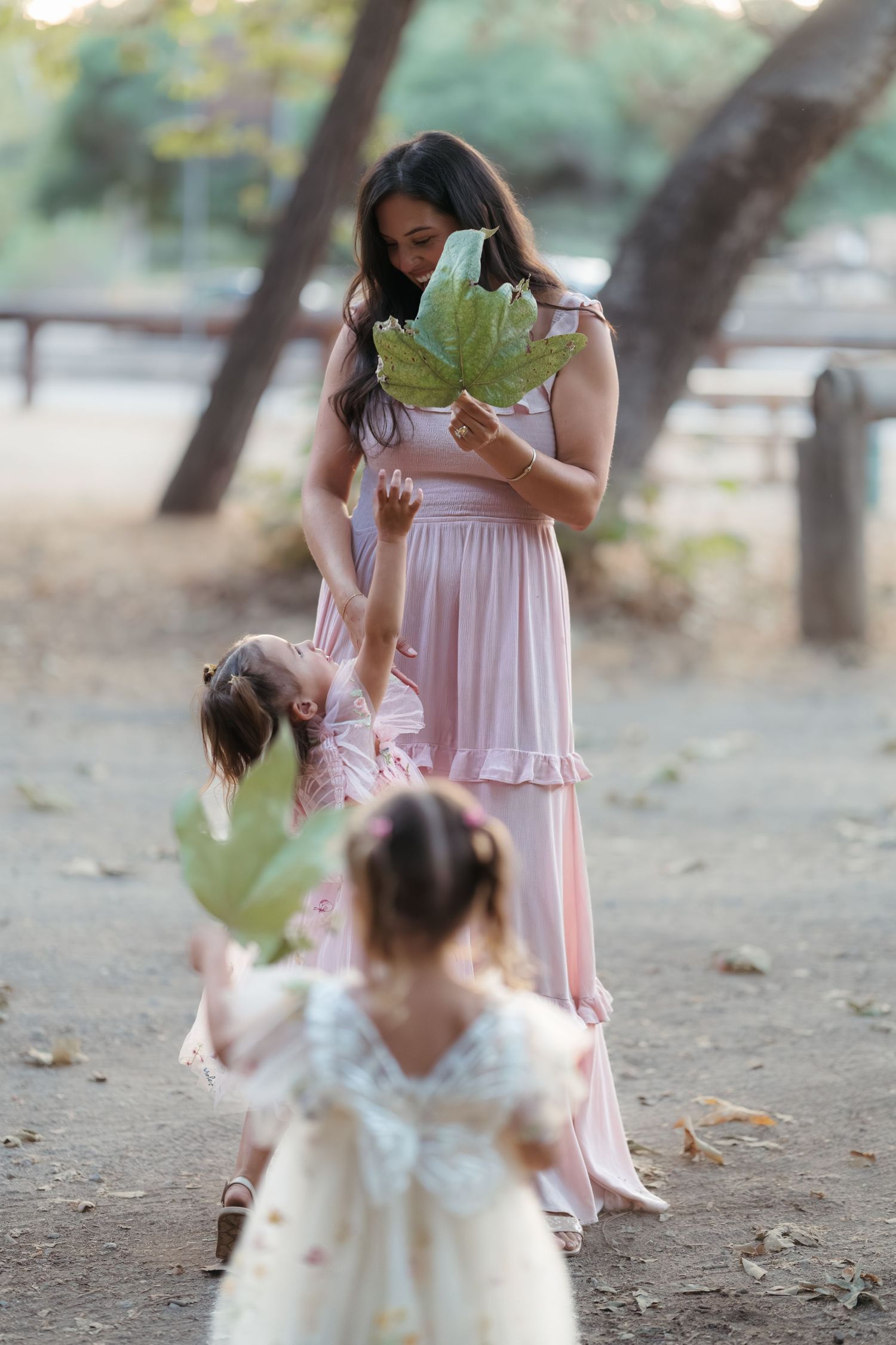 Candid family interaction during outdoor portrait session in pink dresses.