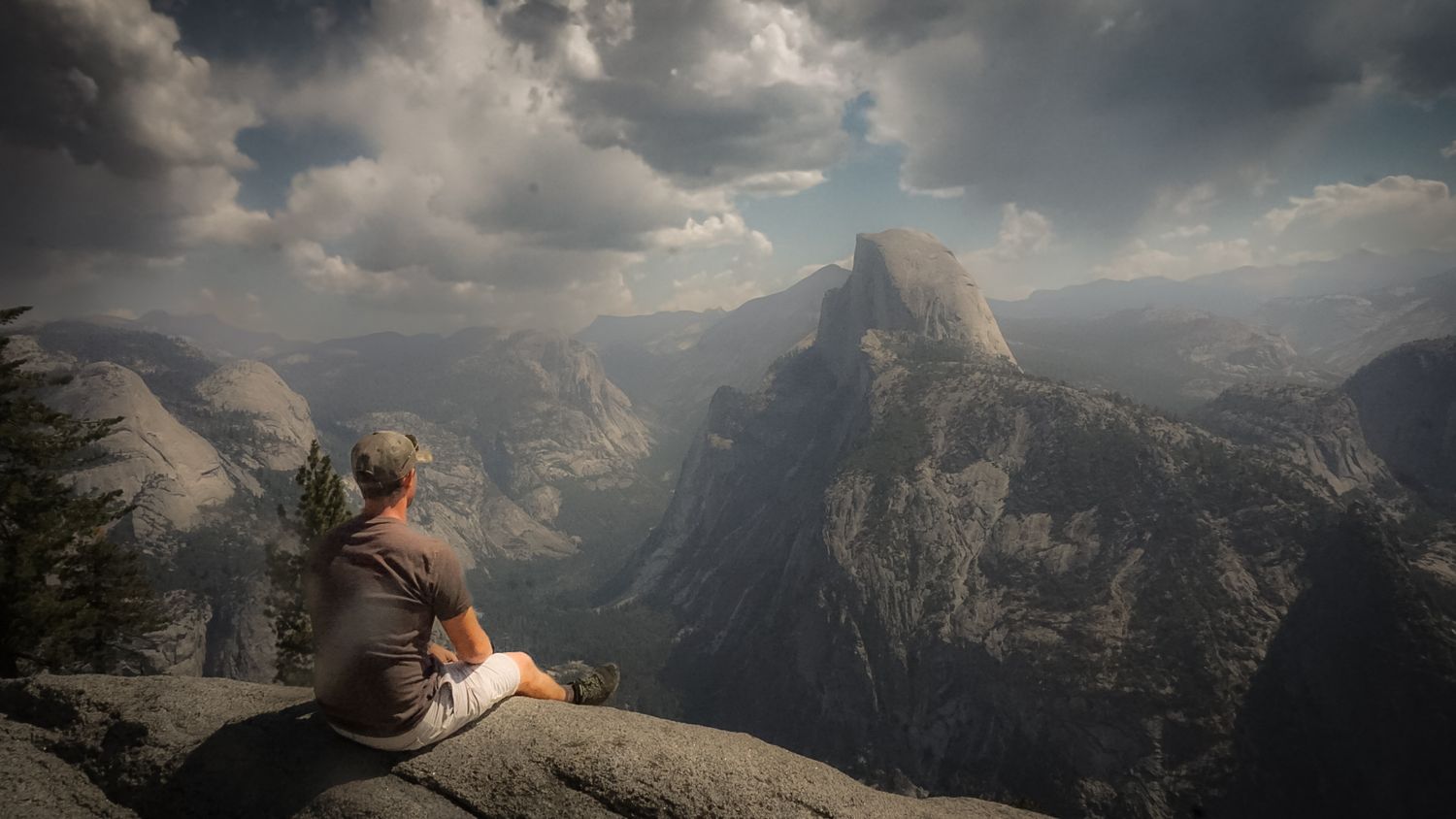 Panoramic view of majestic mountain peaks with dramatic clouds and sunlight breaking through.