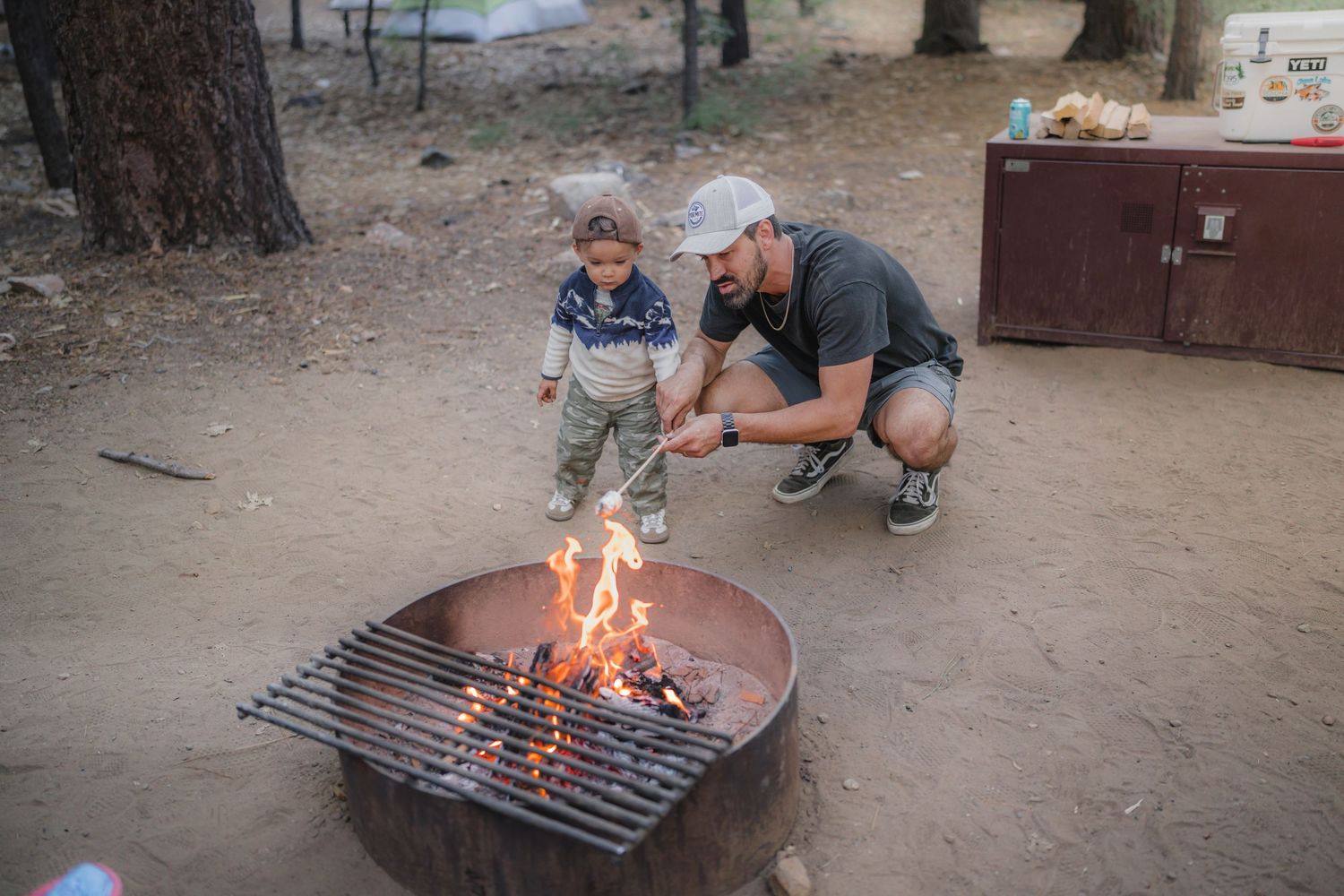 Gathering around a campfire with fire pit in outdoor forest setting.