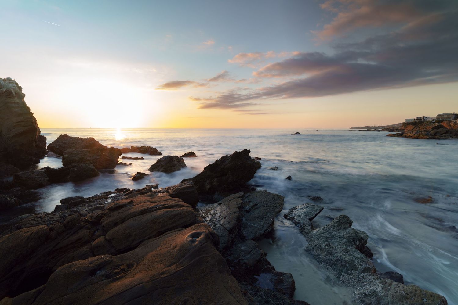 Cinematic landscape photograph of a dramatic sunset over the rocky cliffs and crashing waves of Laguna Beach California by Vince Shewmaker.
