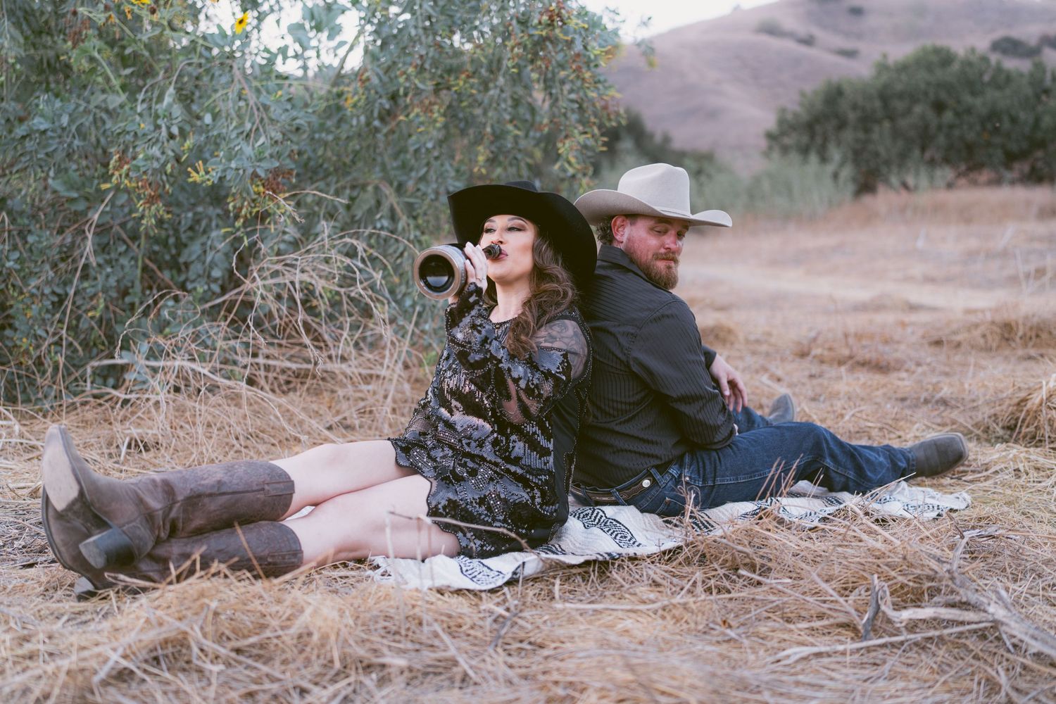 Warm cinematic portrait of a couple embracing in tall grass rolling hills at sunset in the country by Vince Shewmaker.