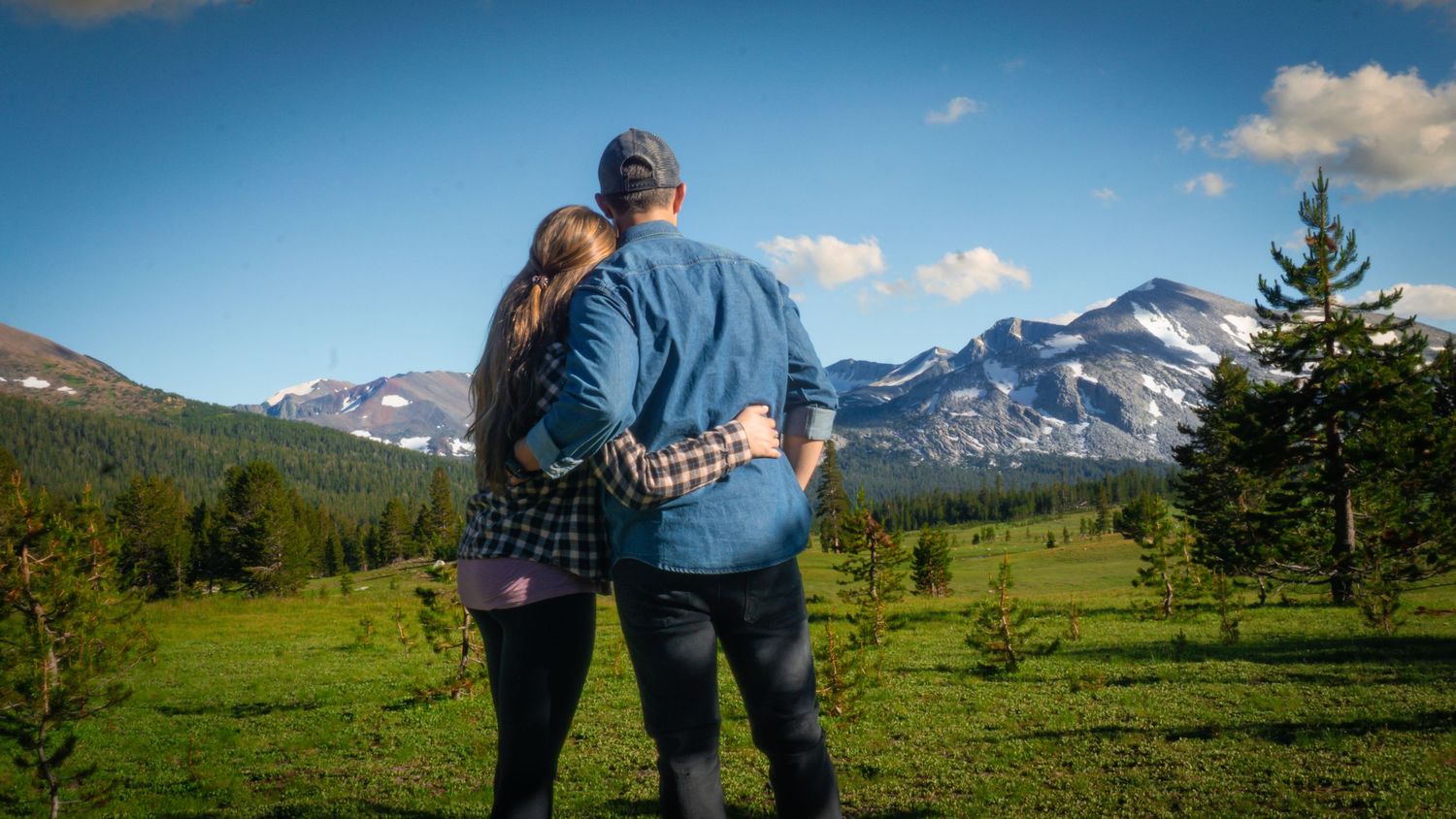 Couple embracing while viewing mountain landscape on sunny day.