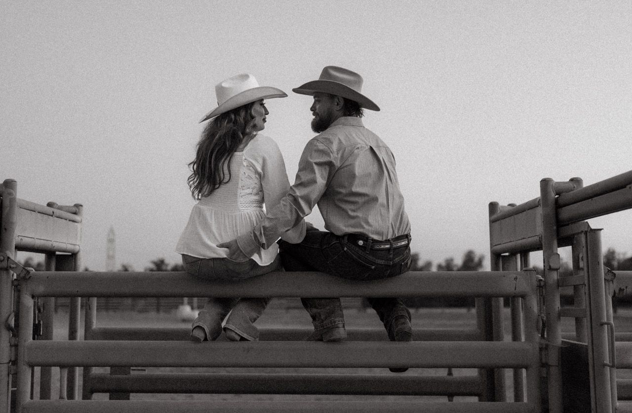 Two figures sit together on a wooden bench in a black and white silhouette scene.