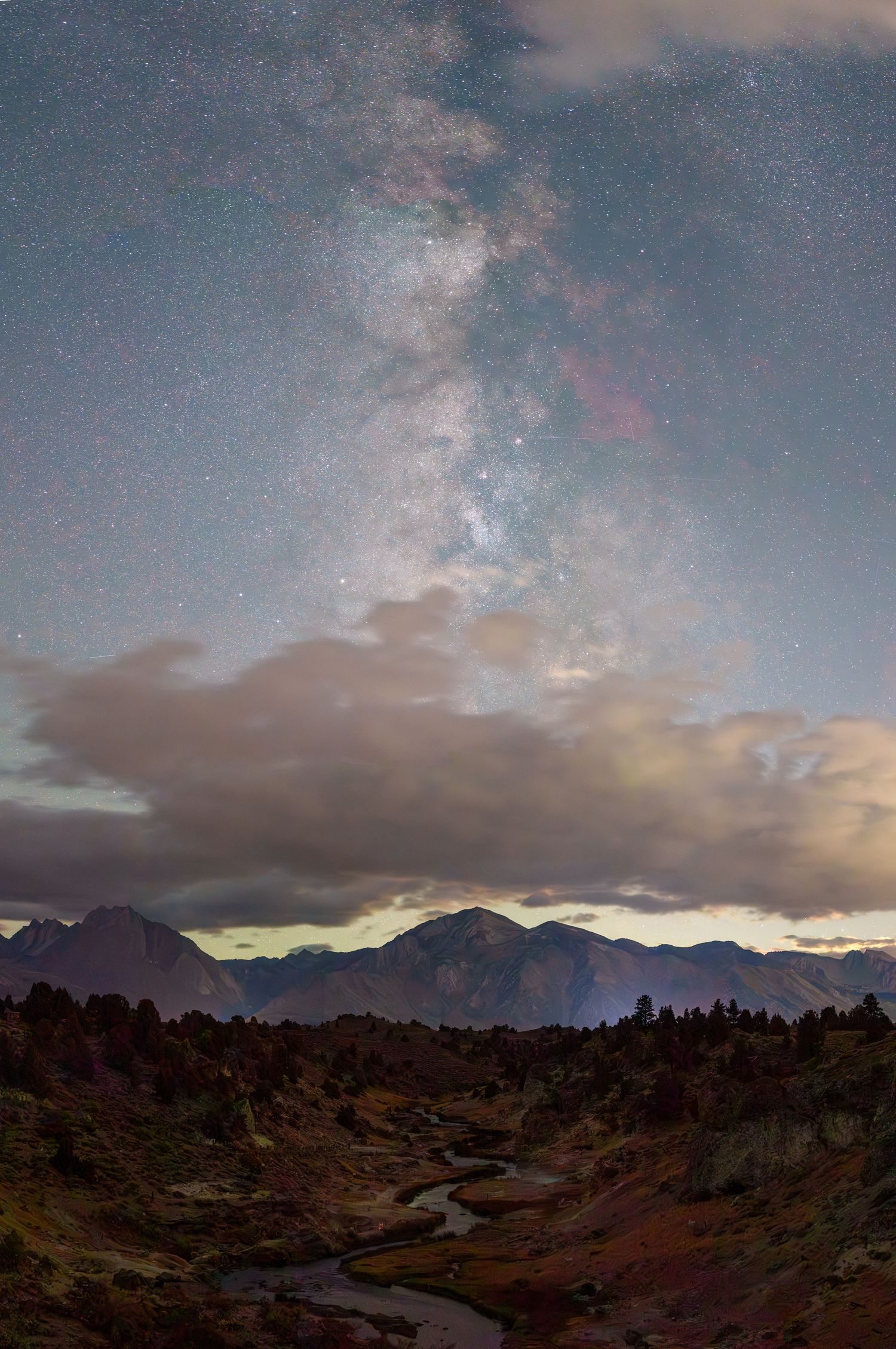 Dramatic wide-angle nature photograph of majestic mountains and stars under a moody sky by Vince Shewmaker.