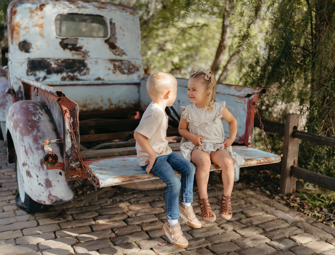Kids sitting on a rustic vintage truck bed in a wooded setting in Temecula, CA