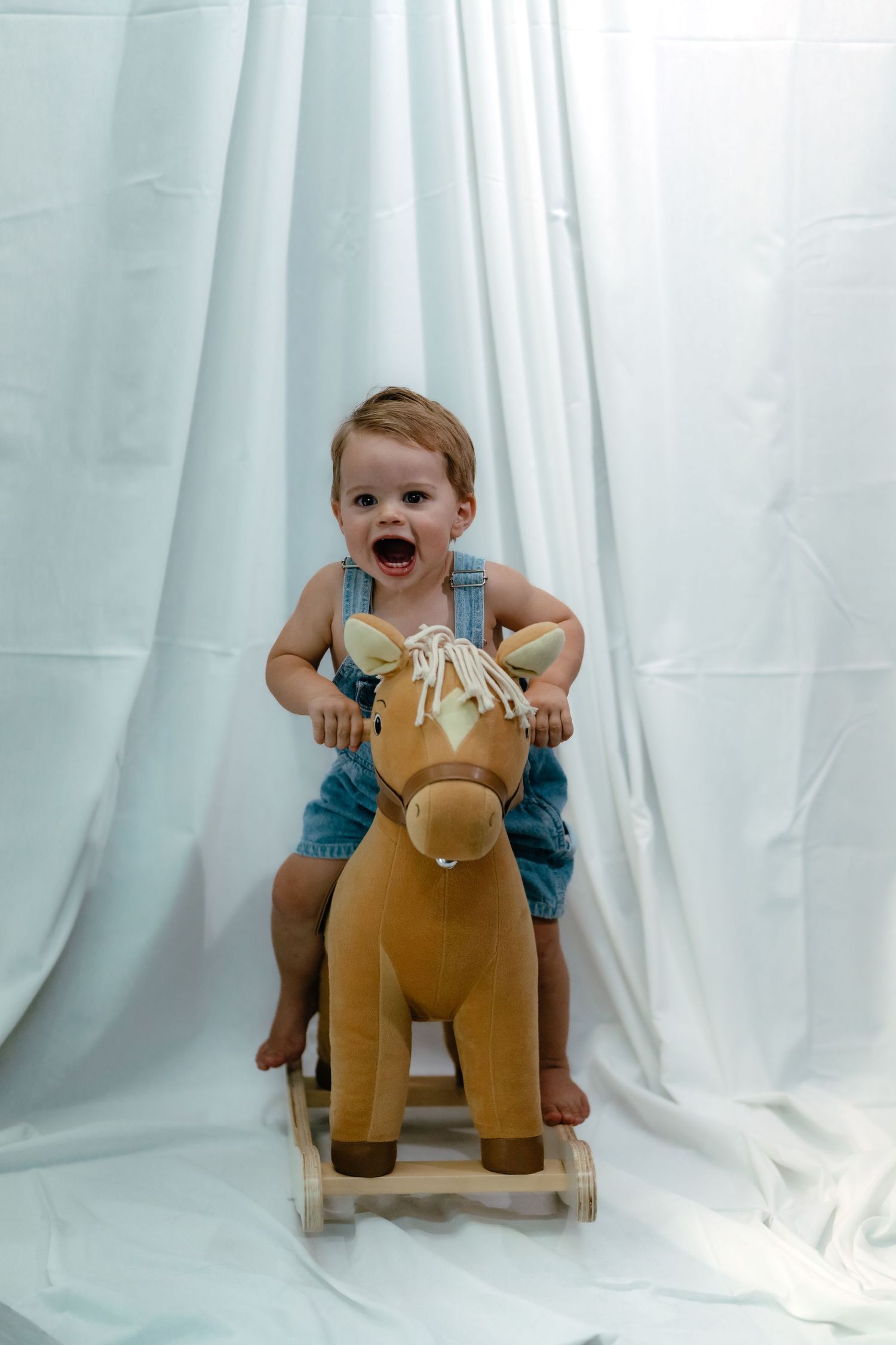 Baby playing with rocking horse toy against white backdrop in progressive action shots.