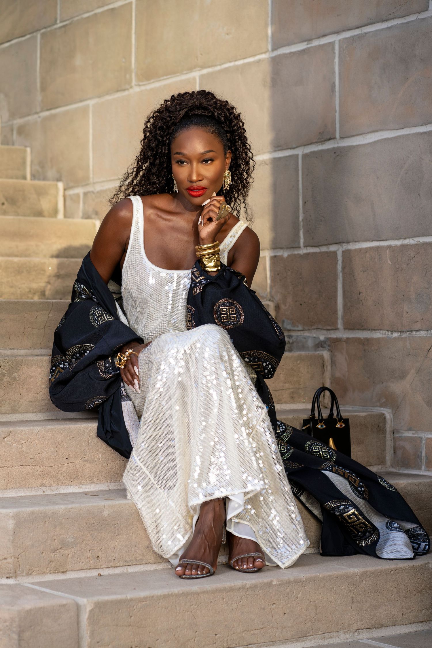 black woman siting on staircase in palm beach island in luxury dress and designer purse and shall.