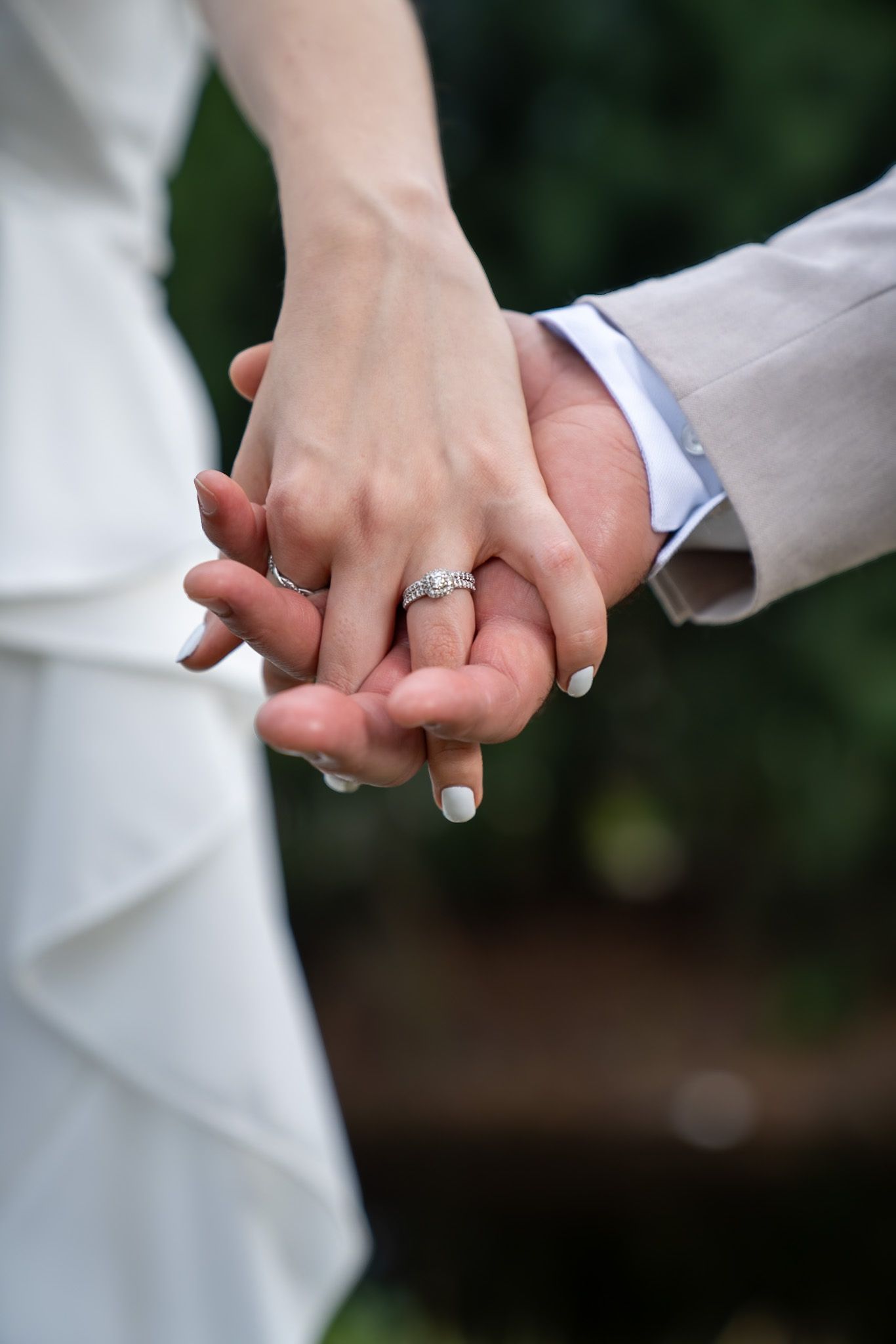 wife and husband just married holding hands displaying wedding ring. Zooming in on hands.