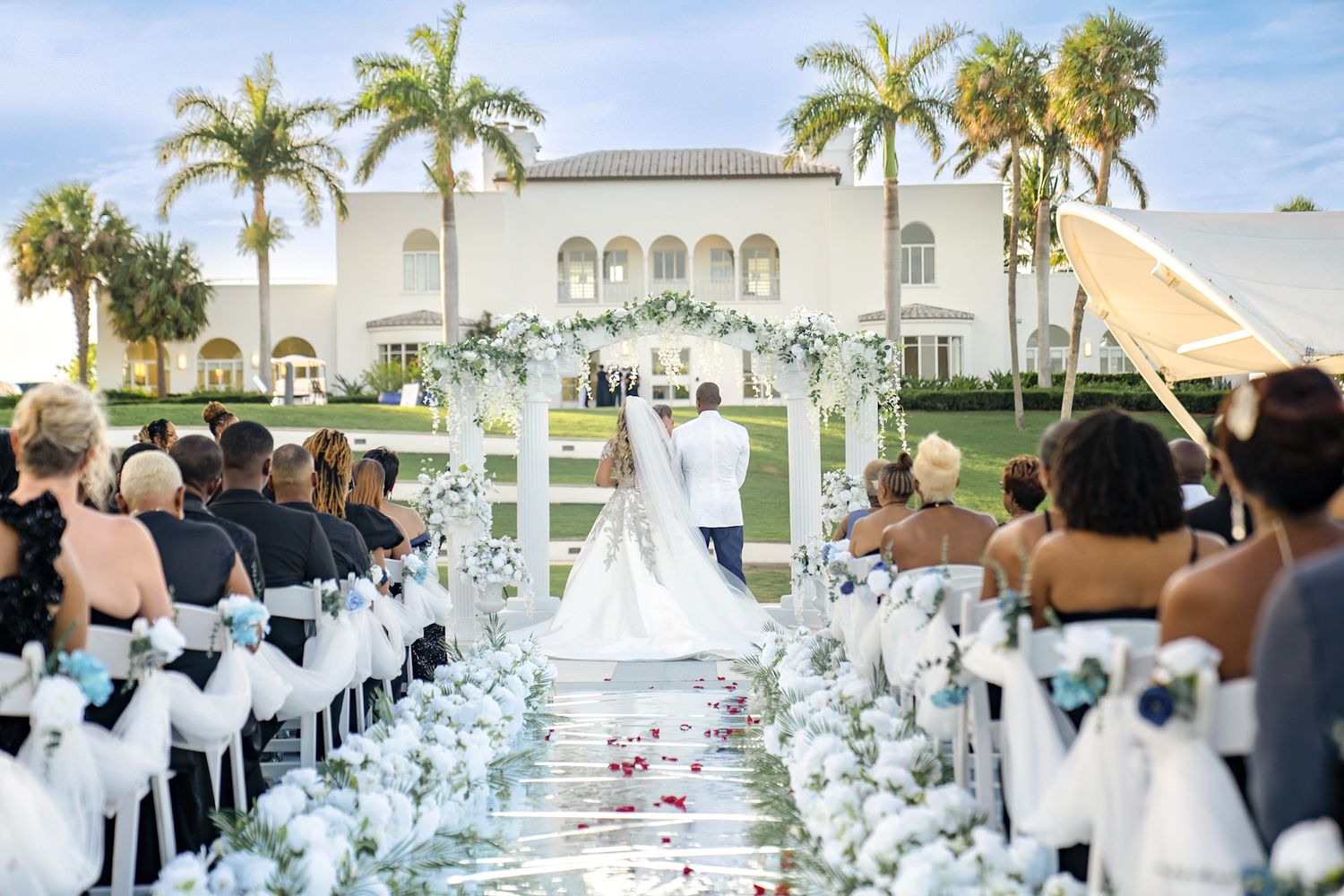 wedding ceremony from perspective of back of isle. showing guests right and left and bride and groom in center up front.