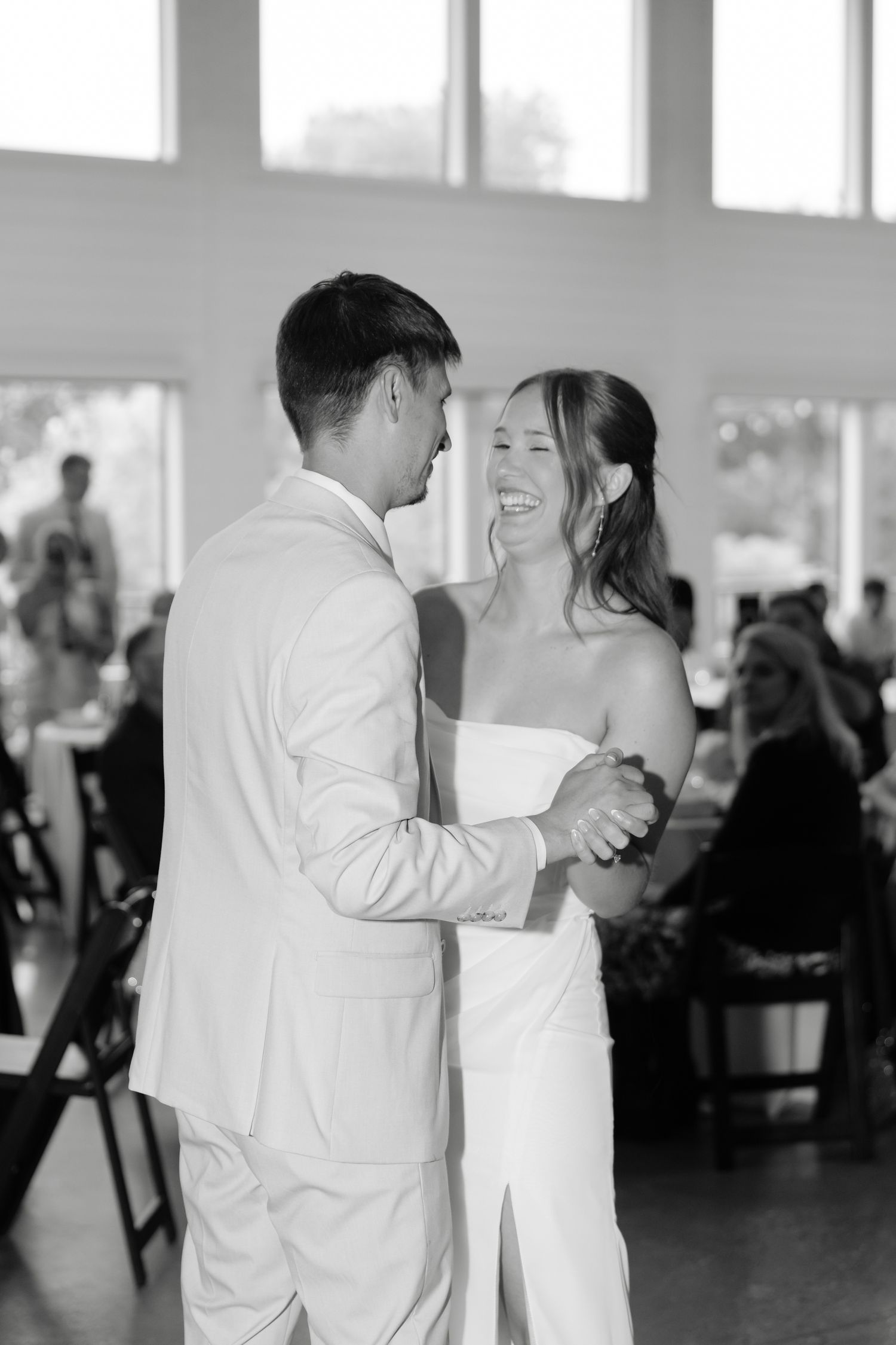 Black and white photo of a bride and groom sharing their first dance at a wedding reception.