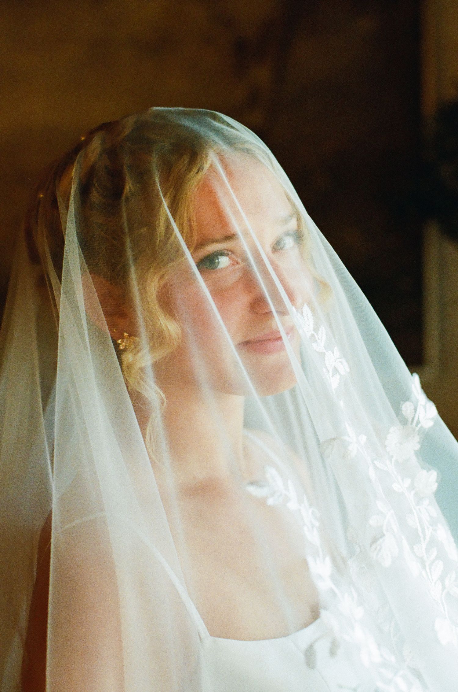 A delicate white bridal veil drapes softly, creating an ethereal effect in natural lighting.