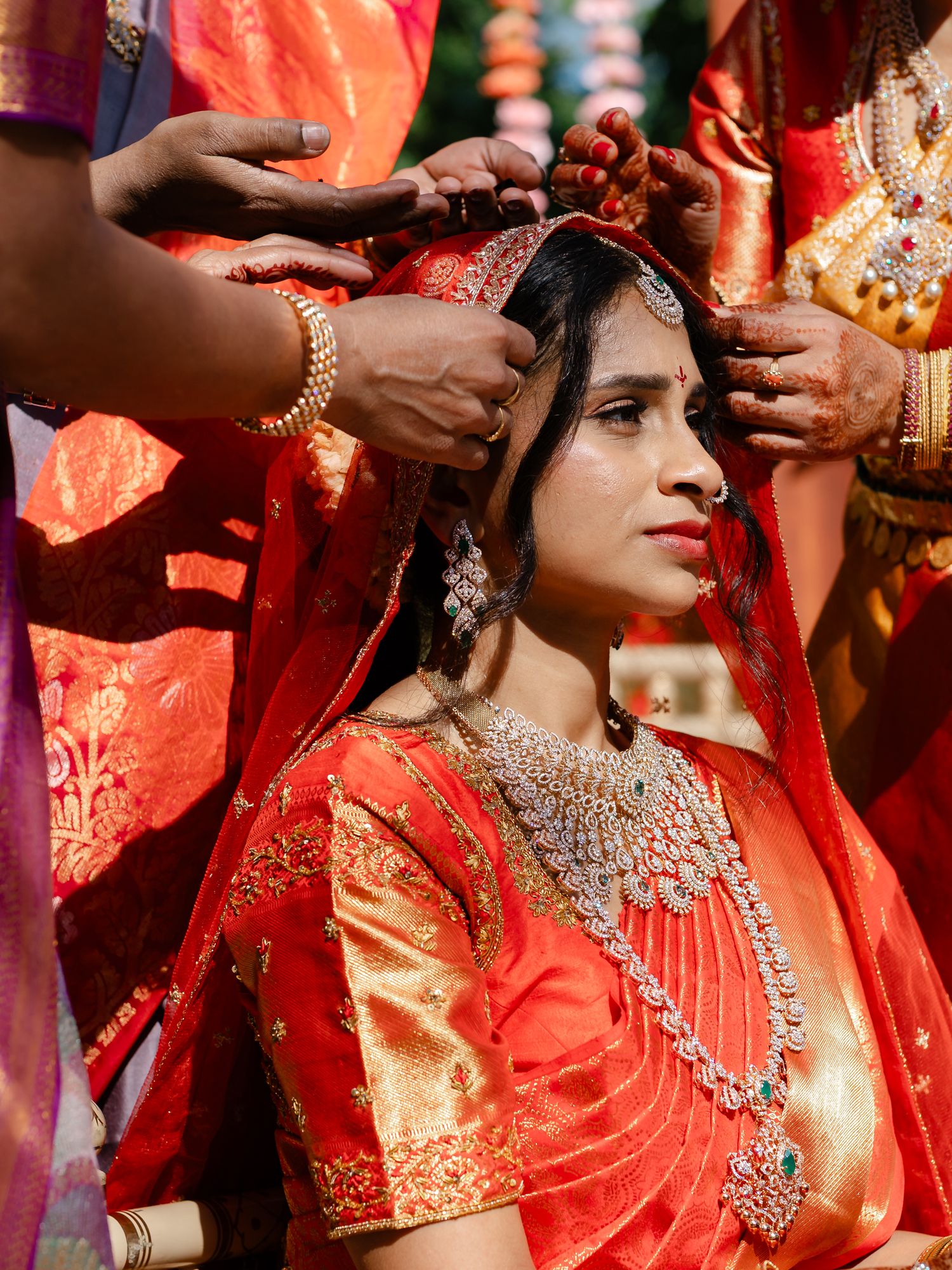Indian bride in red saree adorned with diamond jewelry during traditional Hindu wedding ceremony.