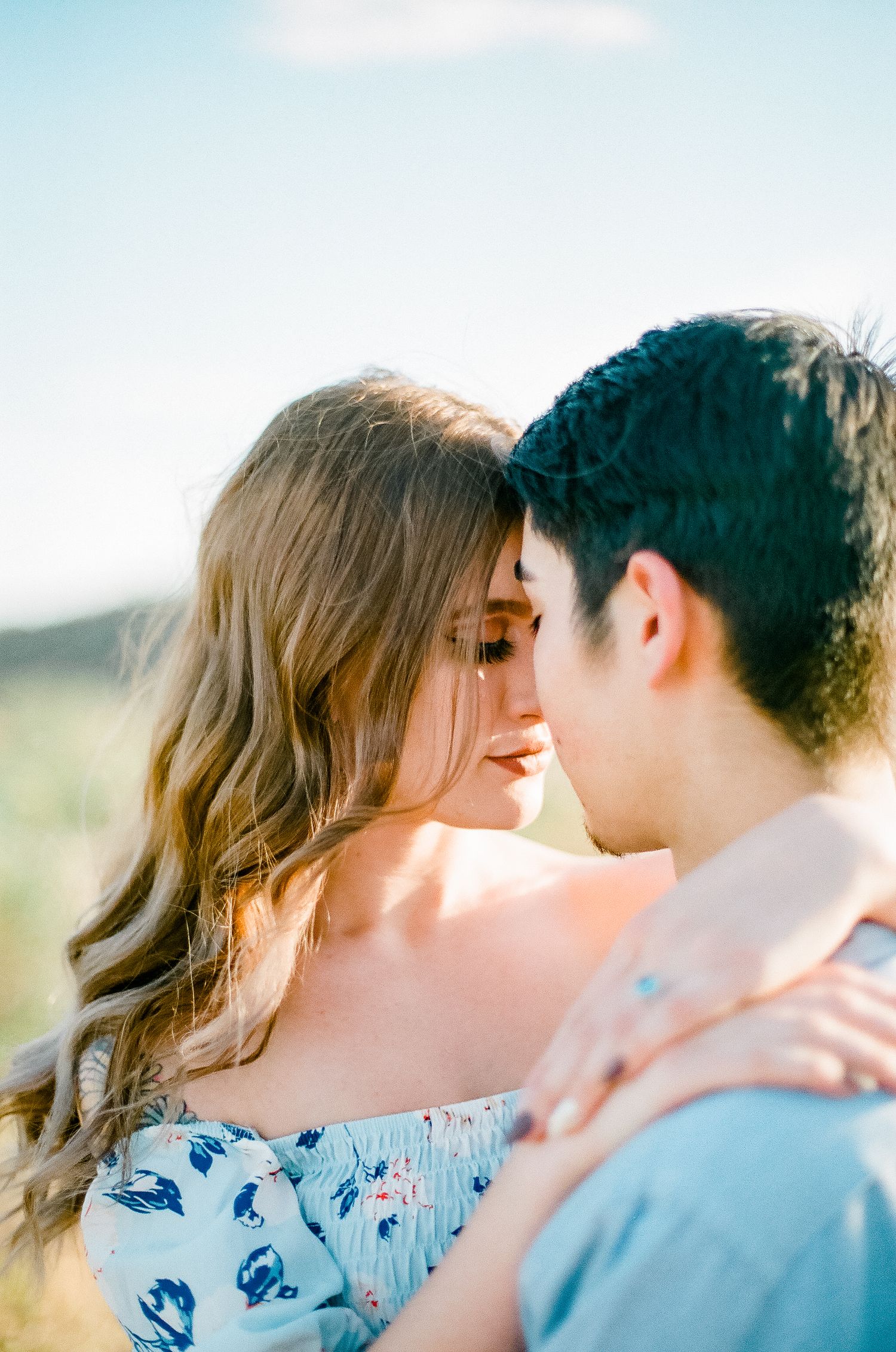 Romantic couple in casual attire sharing tender moments during a sunset photoshoot.
