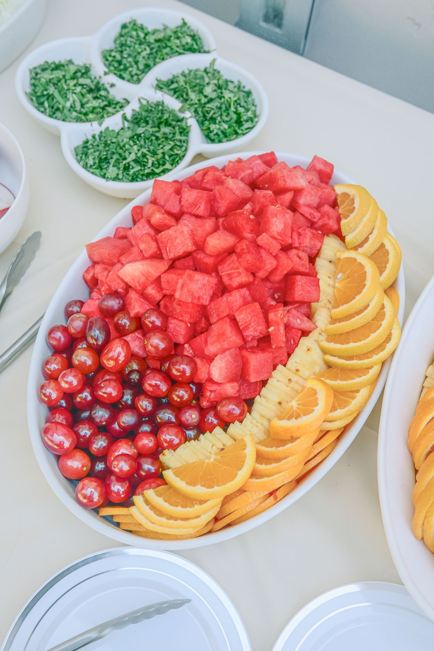 Fresh fruit platter with watermelon cubes, orange slices, berries and garnishes.