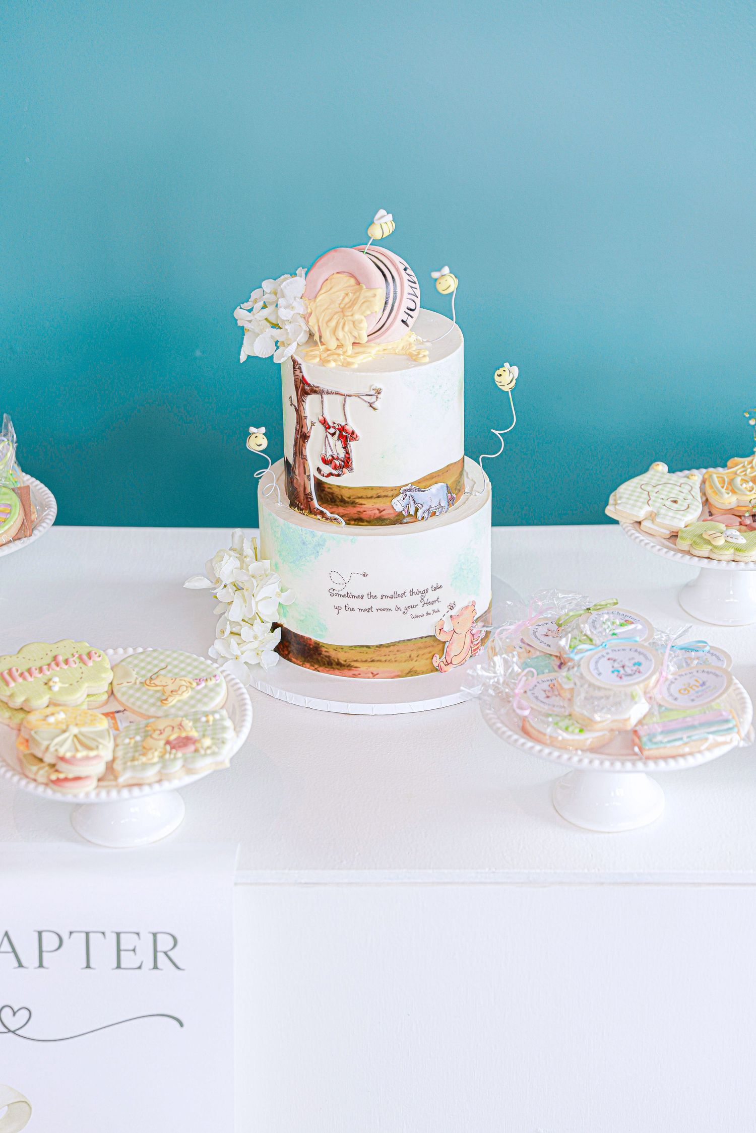 Row of delicate wedding cakes with pastel decorations displayed against a turquoise background.