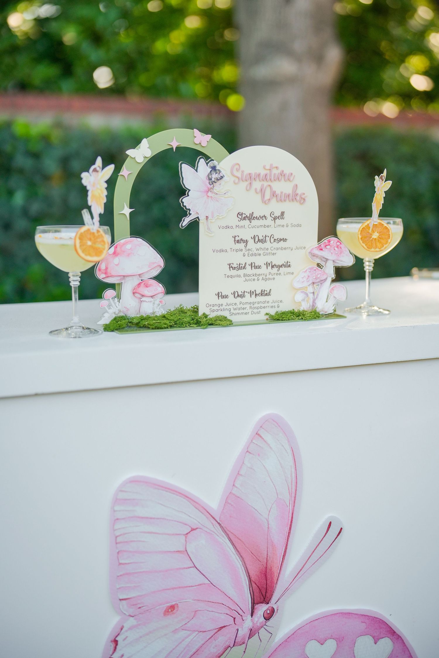 Whimsical drink menu cards with butterfly and floral designs displayed on a white surface.