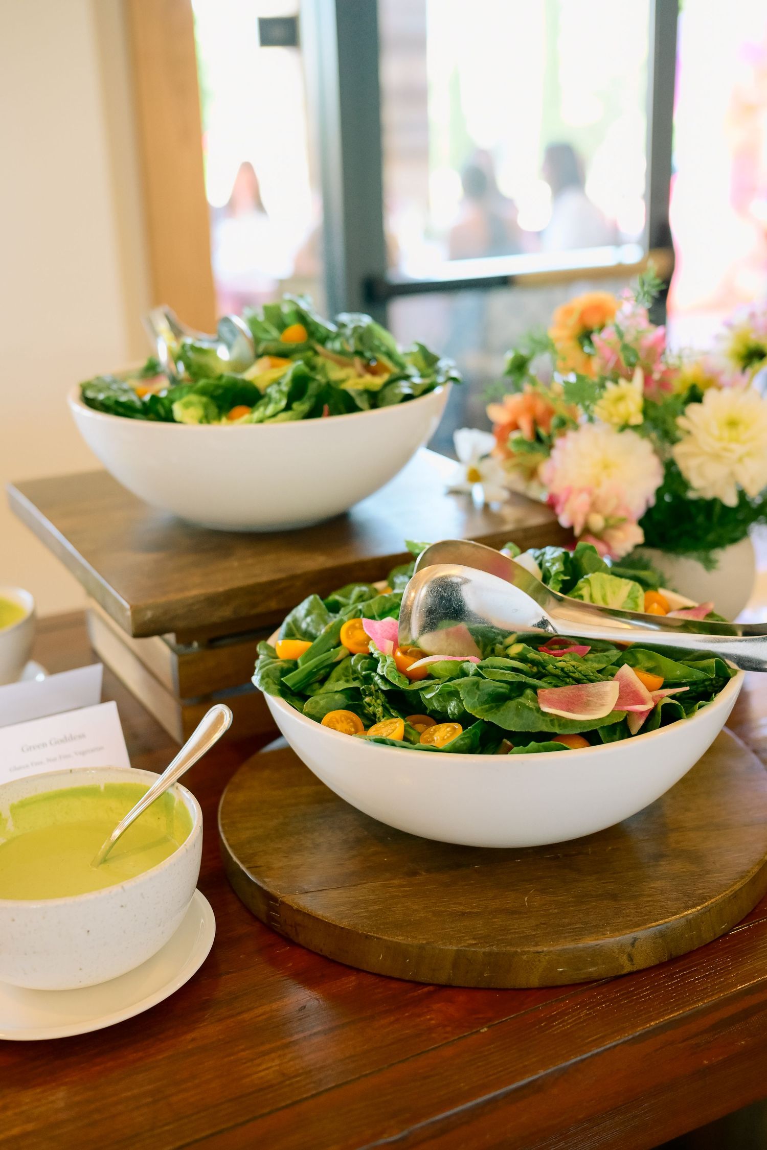 Fresh garden salads served in white bowls on wooden table settings.