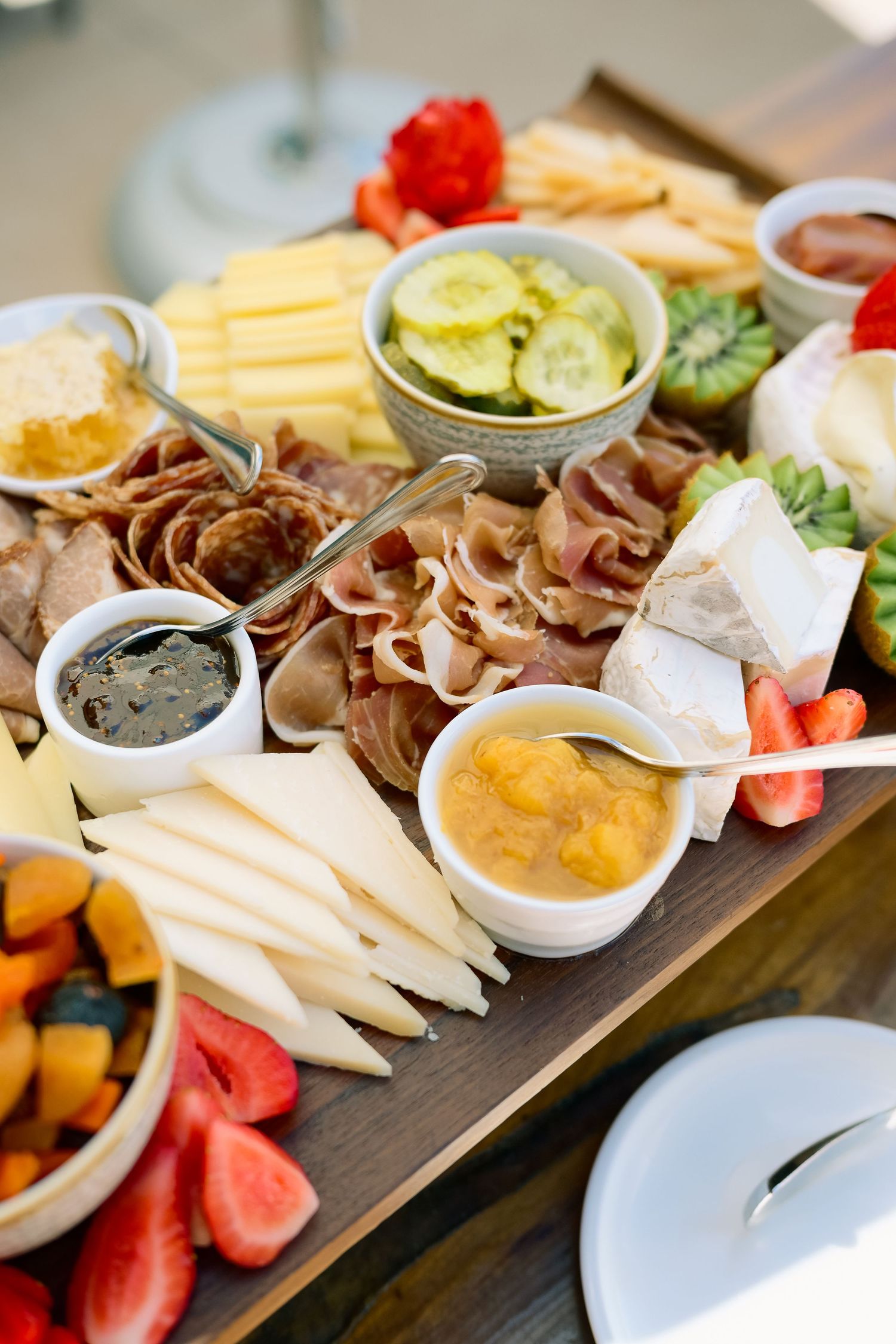 Elegant charcuterie board display with assorted meats, cheeses and fruits on dark wooden platters.