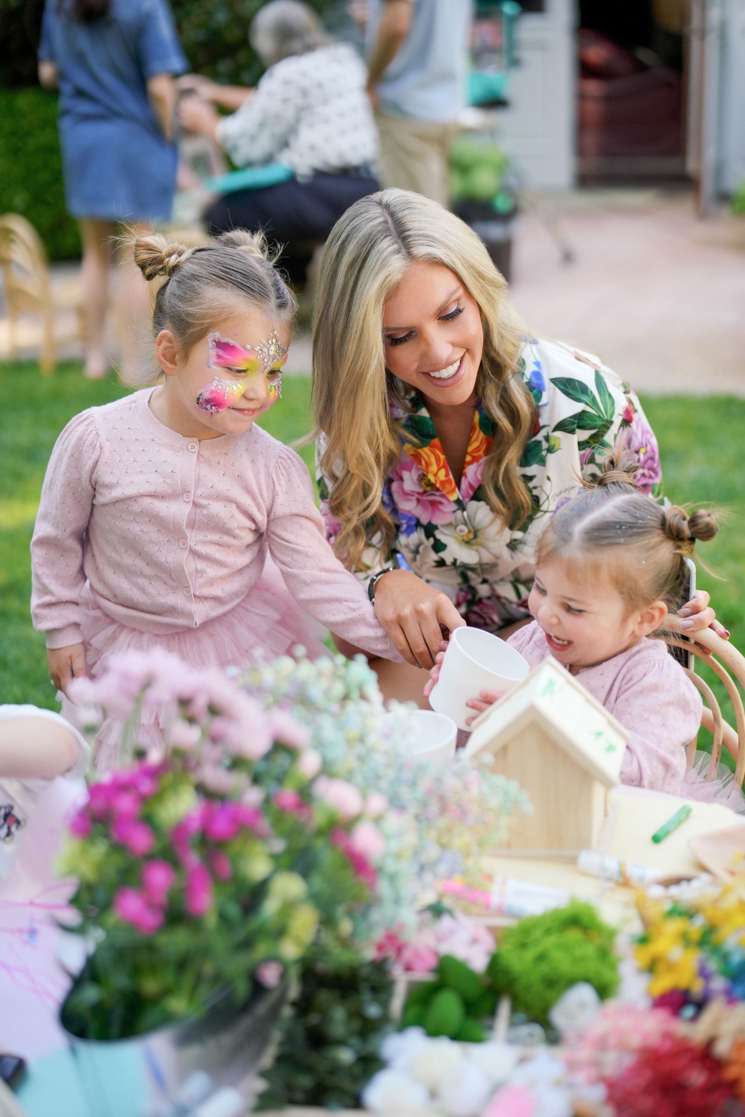 Garden tea party scene with pink floral arrangements and delicate table settings.