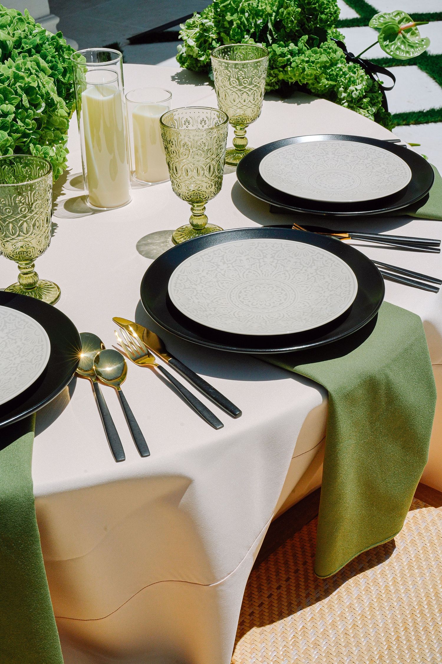 Formal table settings featuring black charger plates, green napkins and vintage glassware.