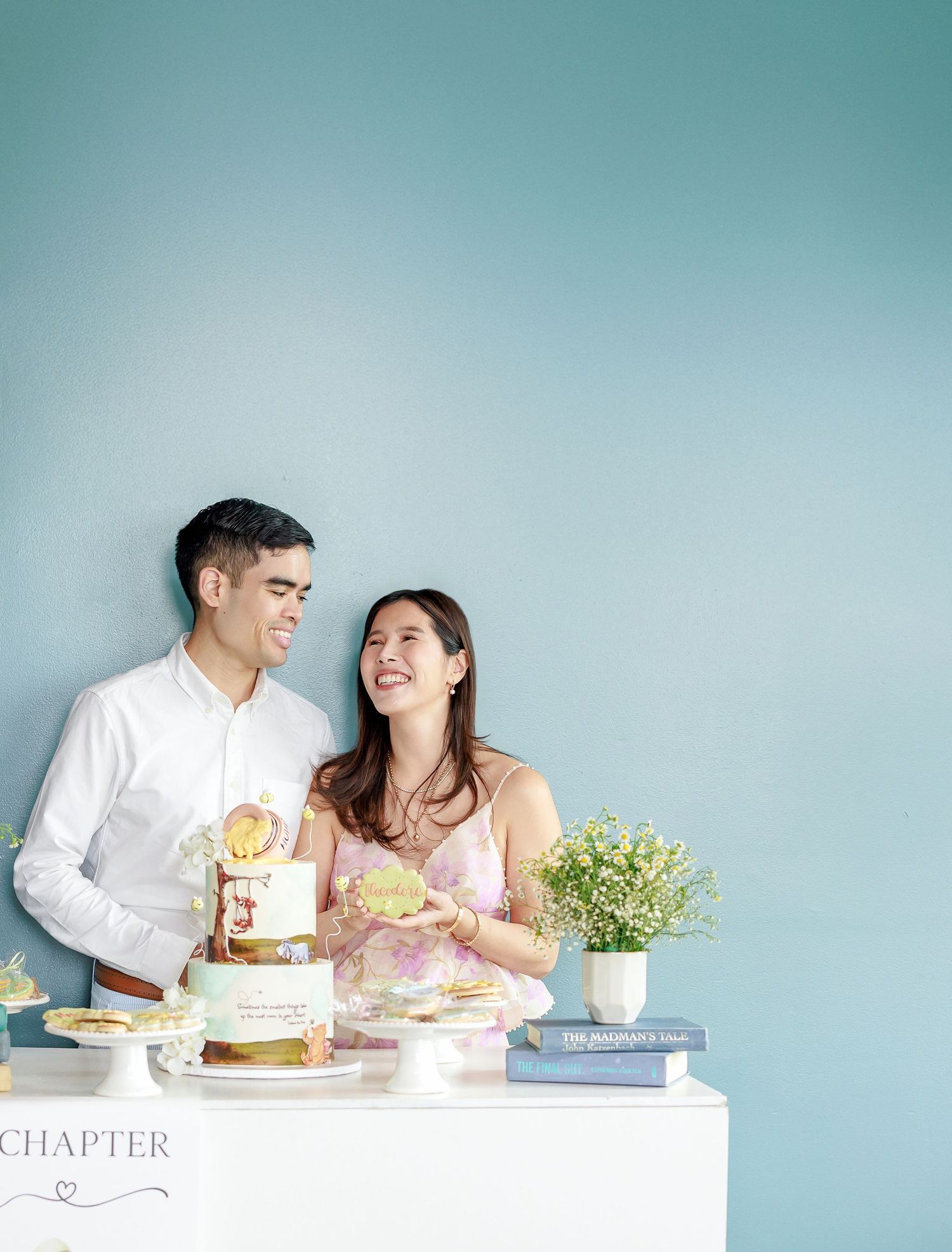 Couple sharing desserts and laughing together at a white table in a bright teal-walled room.