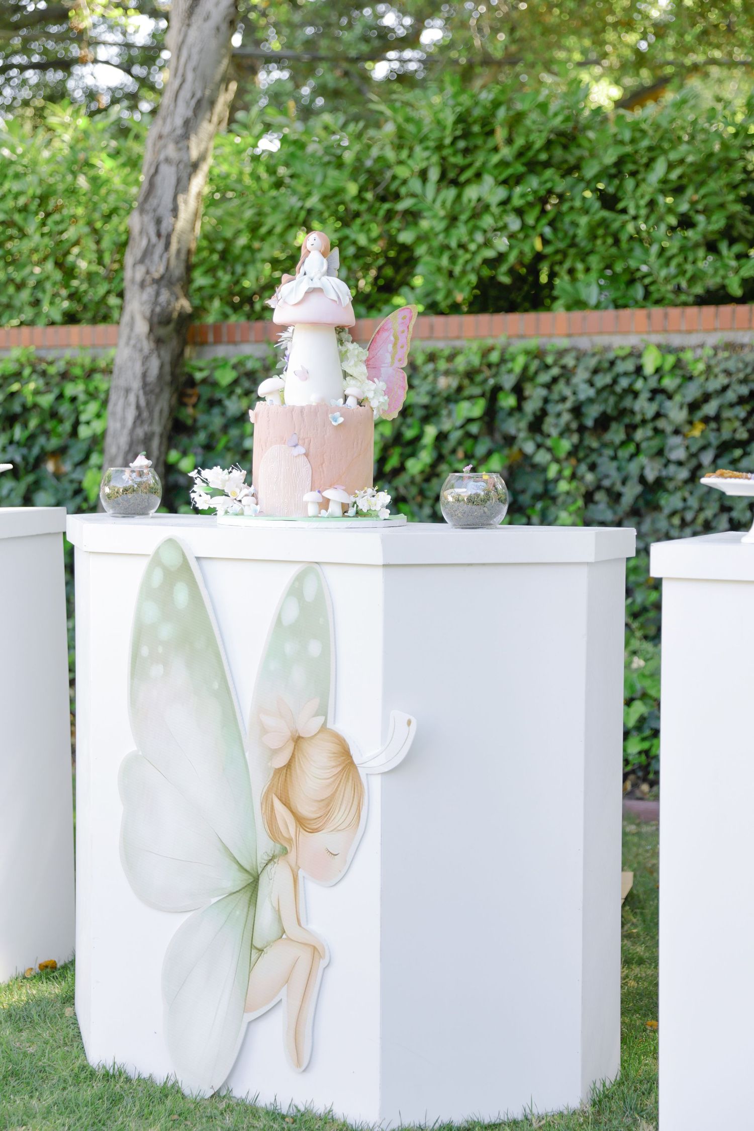 White decorative panels with delicate artwork arranged in an outdoor garden setting.
