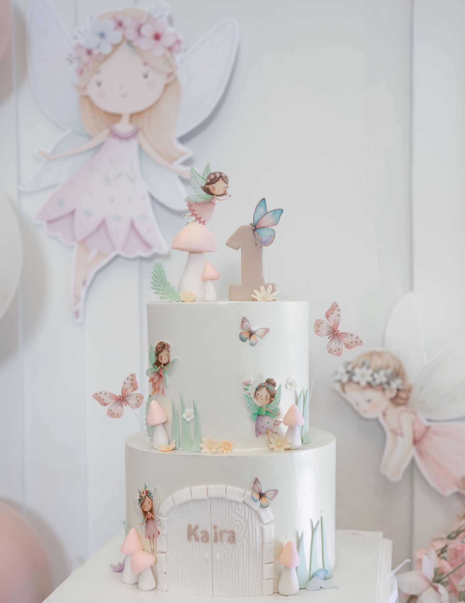 Elegant white wedding cake decorated with delicate pastel butterflies and floral accents on a light background.