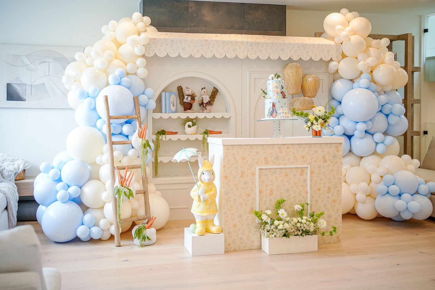 Elegant party setup with white and pastel blue balloon arch decorations in an indoor venue.