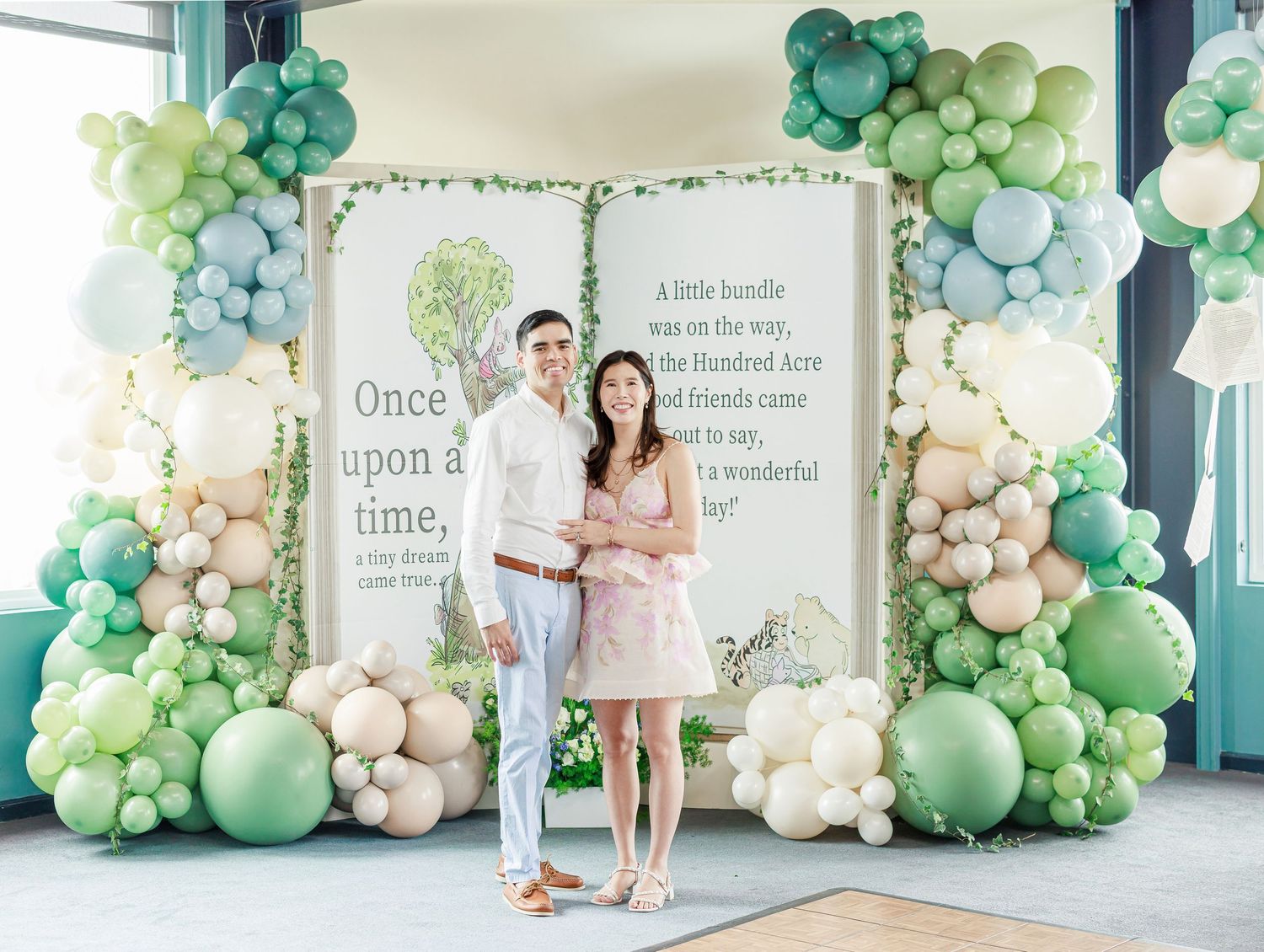 Elegant balloon arch display in mint green and white colors with a storybook theme backdrop for a special event.