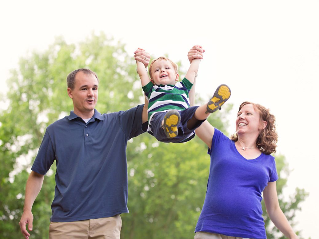 South Lyon Michigan family portraits of little boy laughing and swinging in parents arms by Brighton MI, family photographer