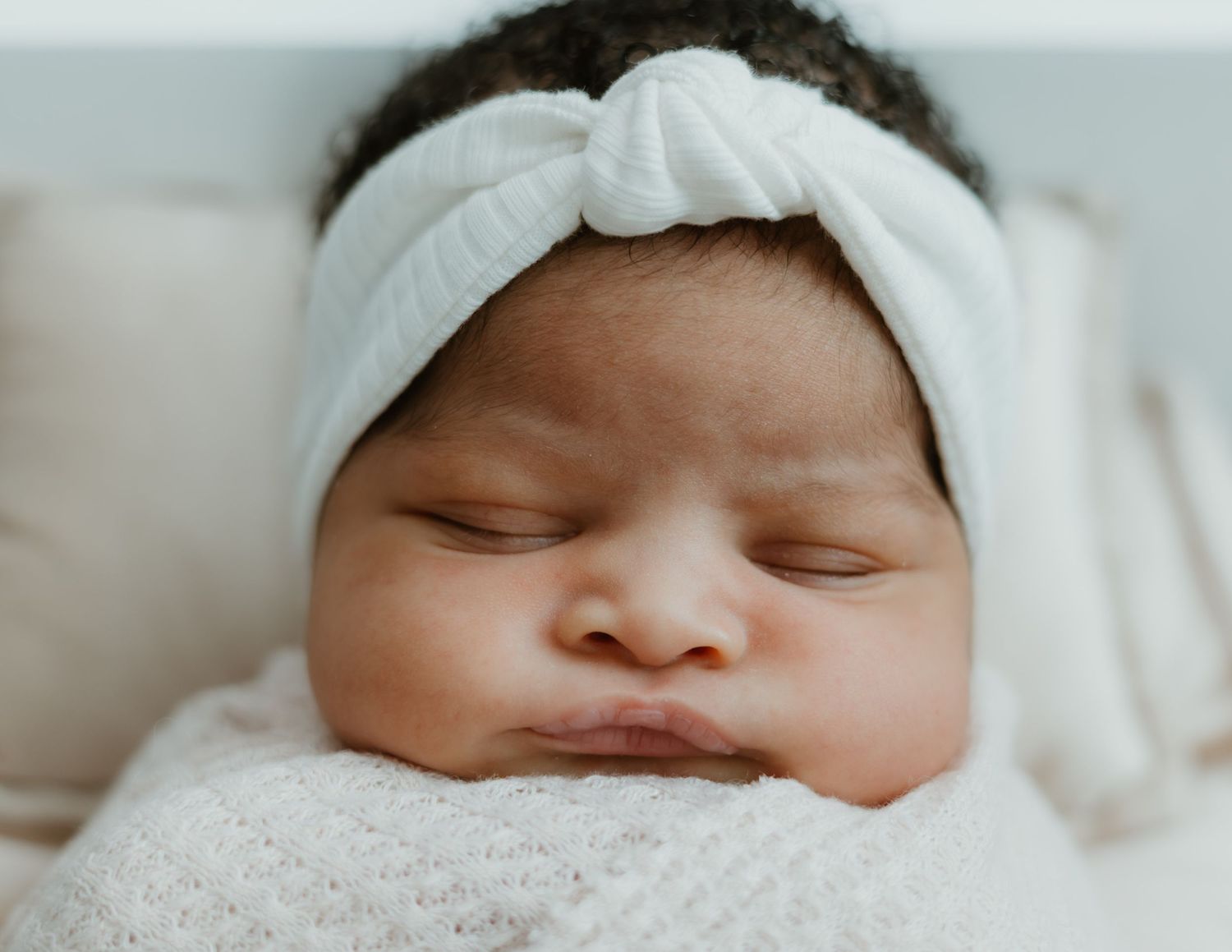 A series of close-up portraits showing different angles of a sleeping newborn baby wearing a white hat.