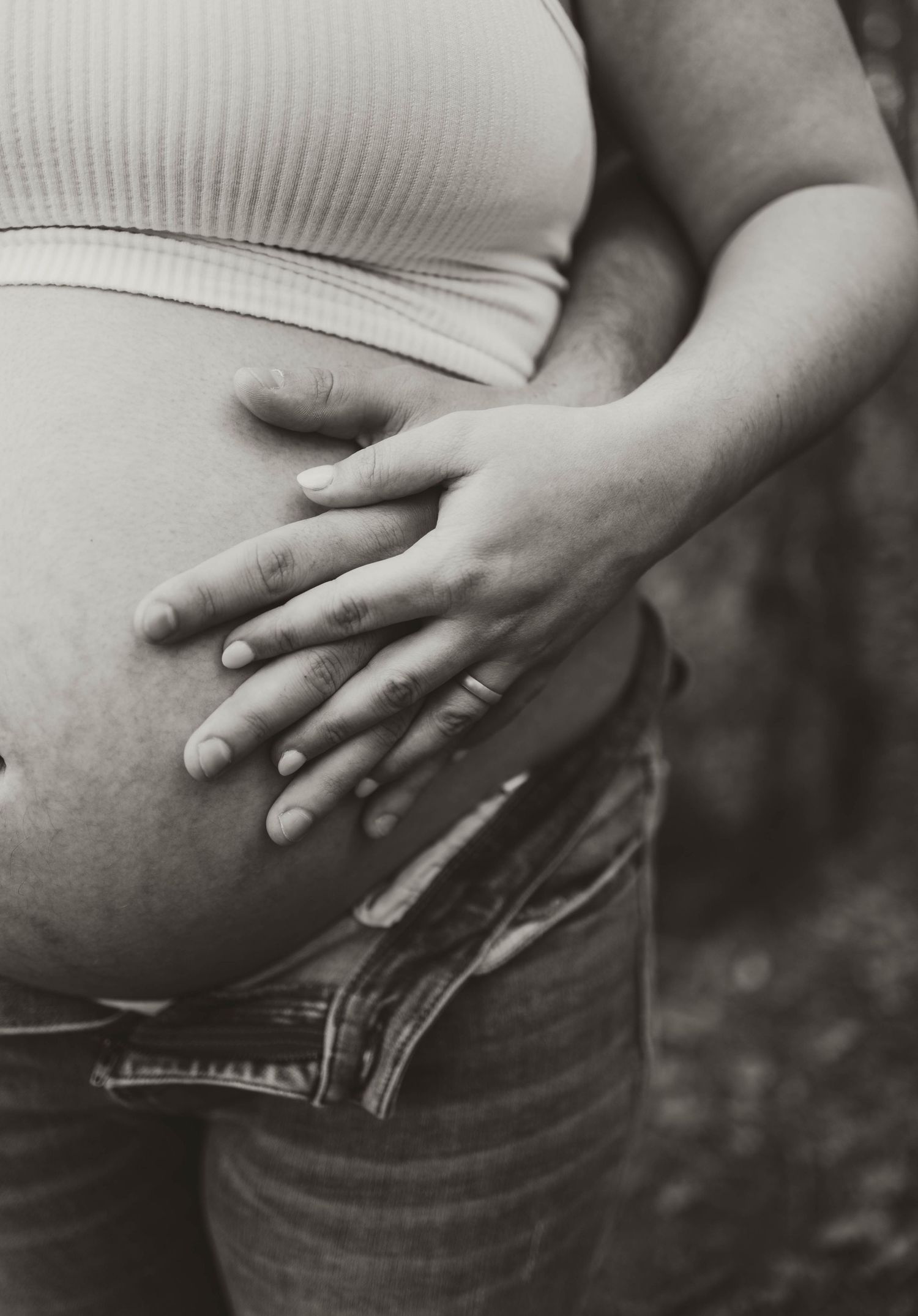 Black and white close-up of hands cradling a pregnant belly.