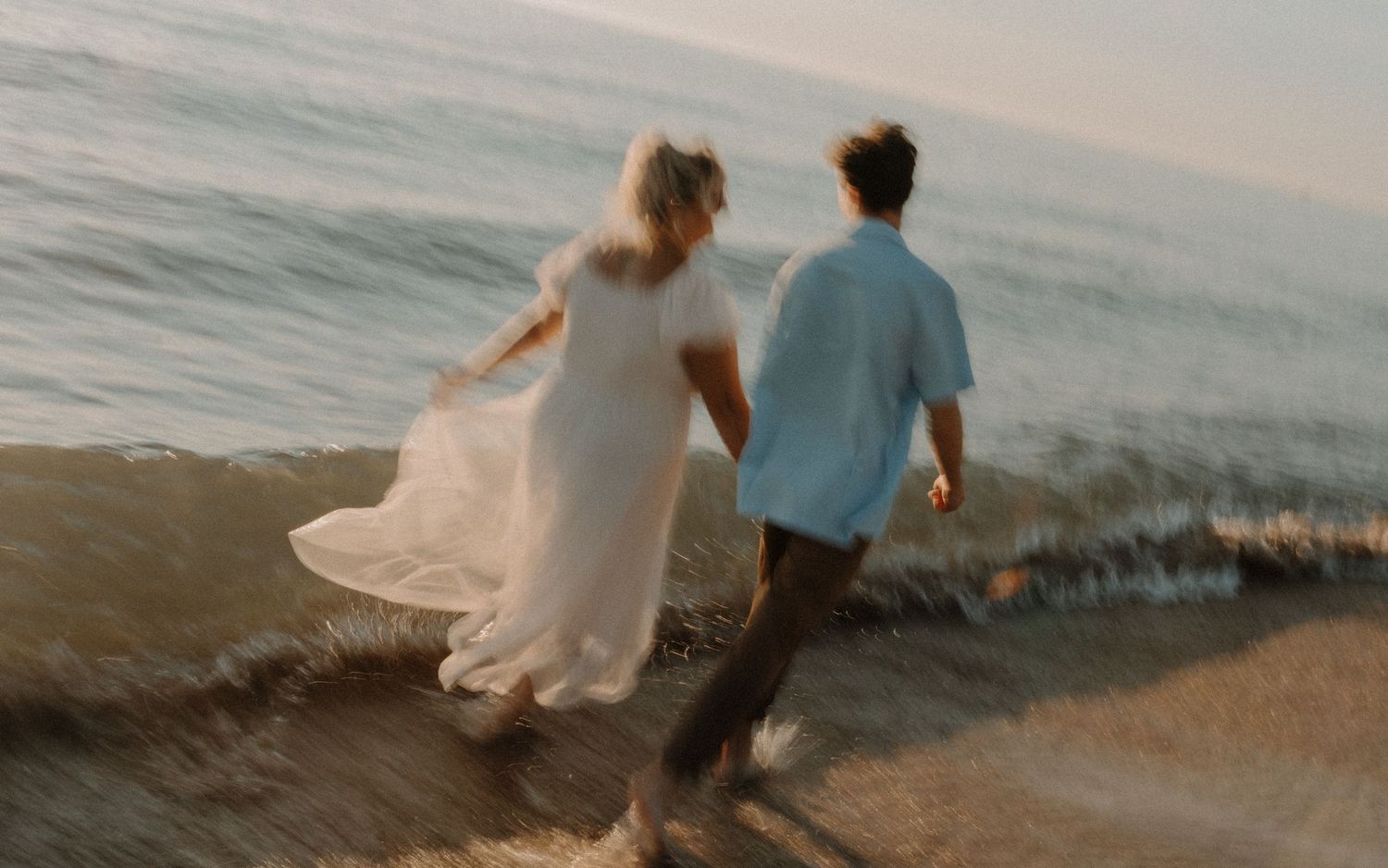 Couple walking together on a scenic beach at sunset, holding hands and enjoying romantic ocean views.