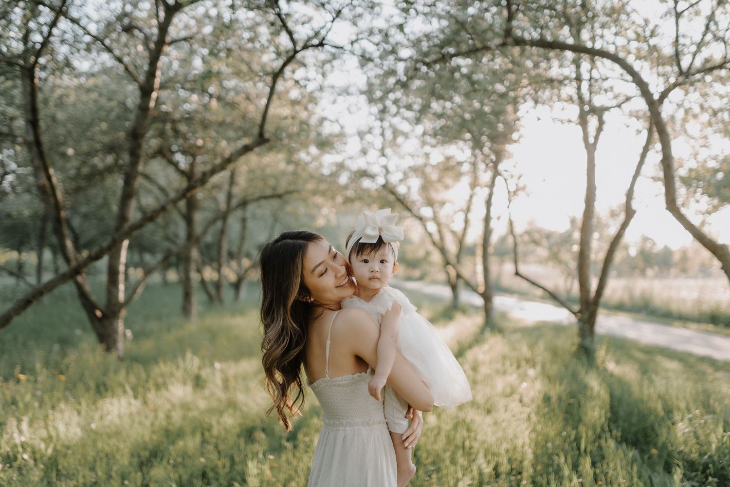 Romantic couple embracing in a sunlit outdoor setting among olive trees during a golden hour photo session.