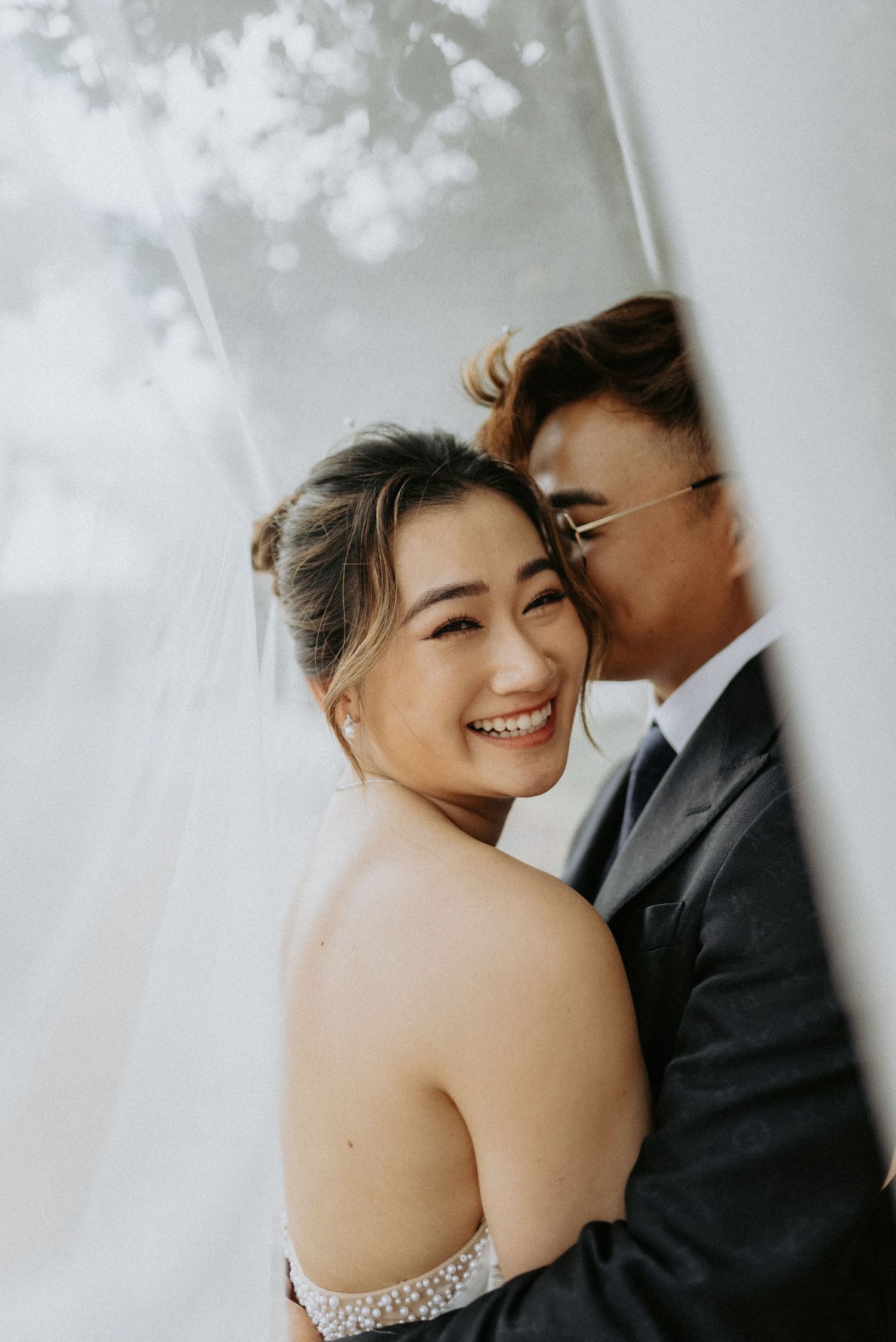 Artistic wedding portrait capturing joyful moments in soft lighting.