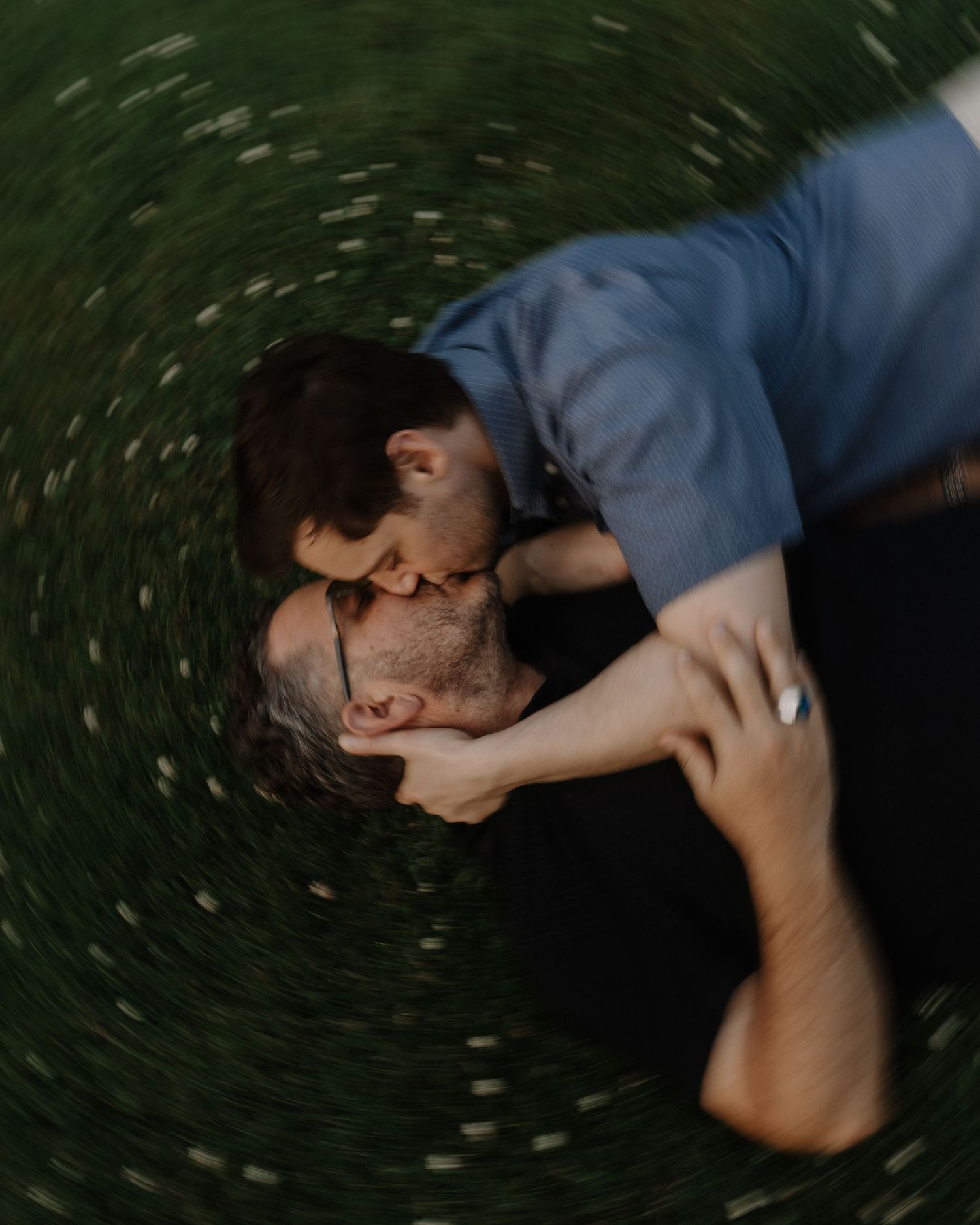 Artistic spinning motion blur photograph creating a circular effect against dark background. LGBT couple, engagement photoshoot.
