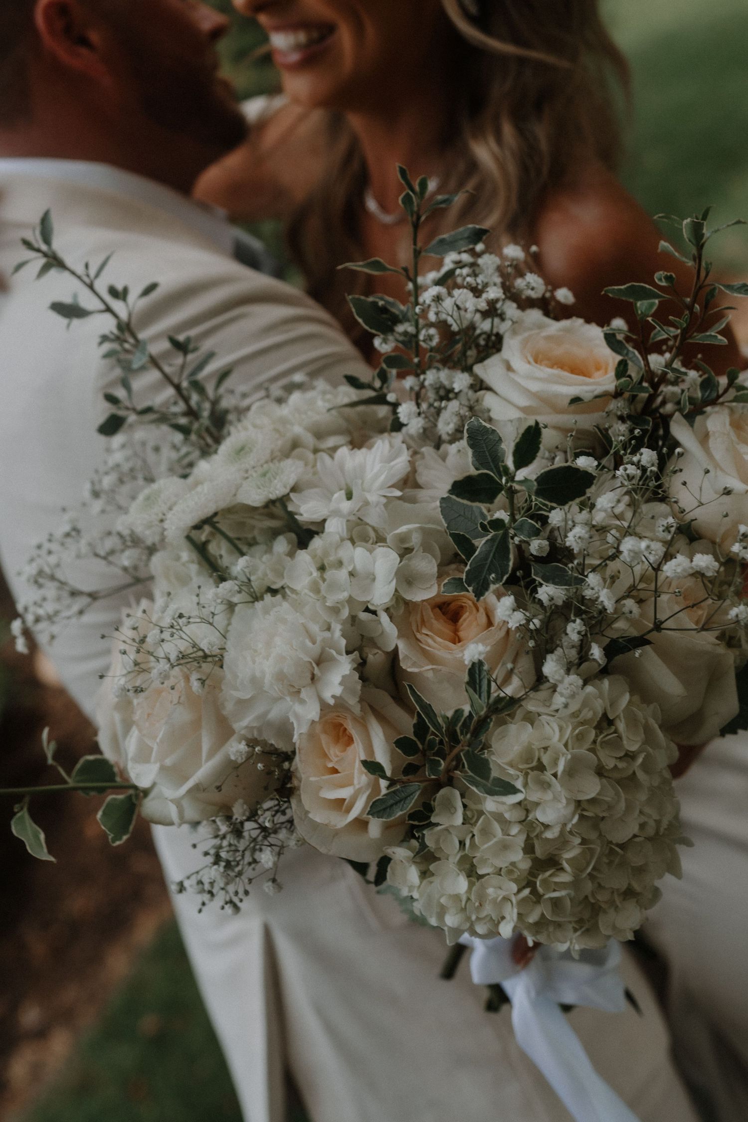 A series of elegant white wedding bouquets with roses and greenery arranged side by side.