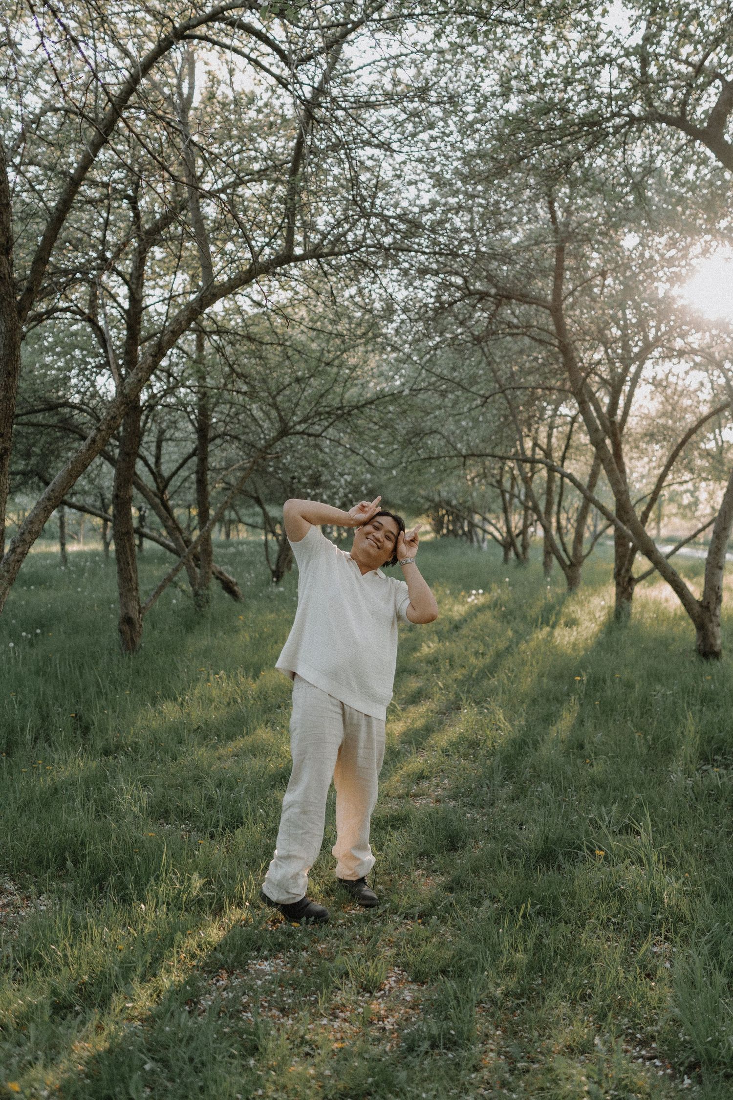 Ethereal sequence of figures dancing through a sunlit orchard with blooming trees.