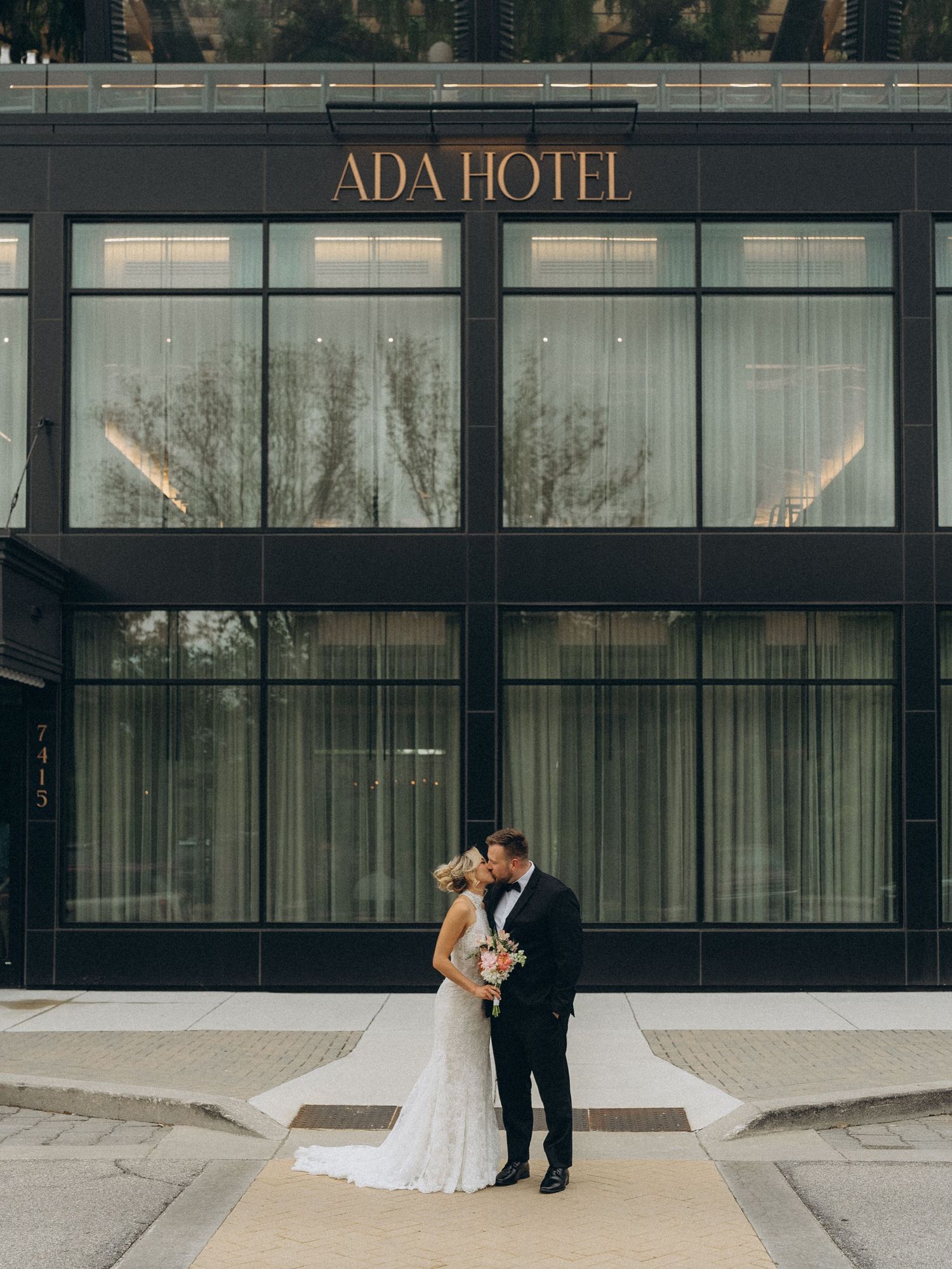 Couple kissing in front of the ADA Hotel on their wedding day.