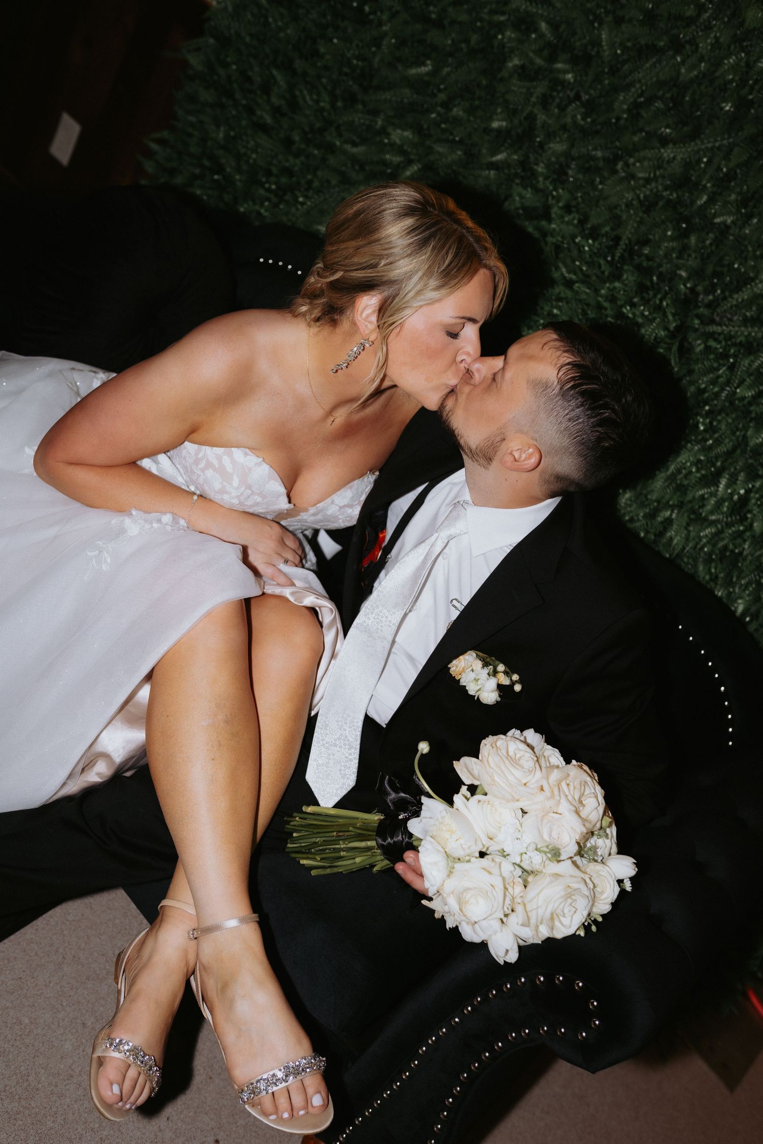 Romantic evening portrait showing sparkly shoes and white bouquet against formal attire.