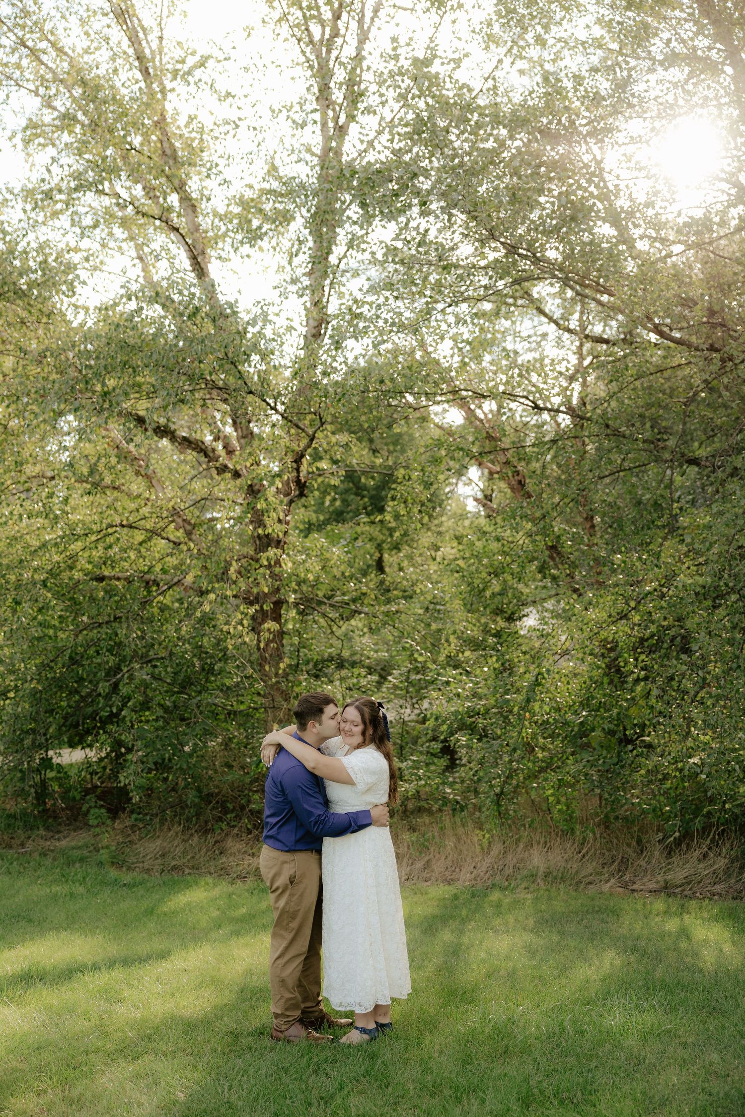 A couple walking hand in hand through lush green foliage on a summer afternoon.