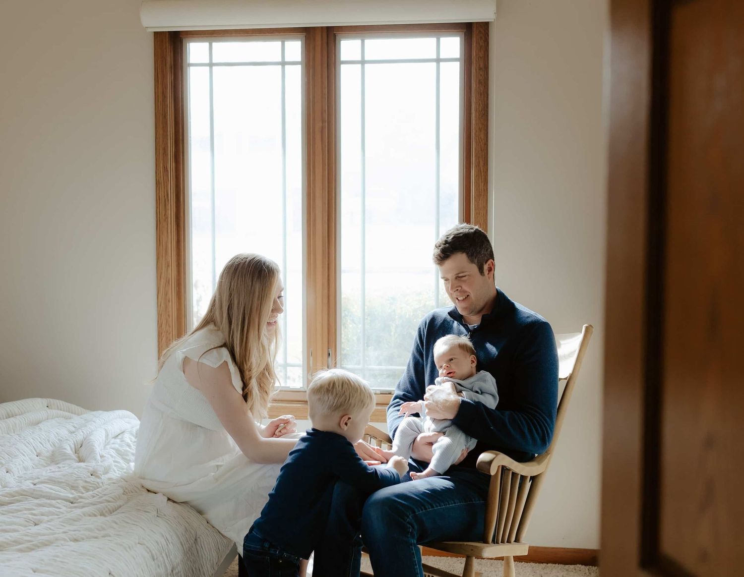 A series of candid family lifestyle photos showing intimate moments of an at home newborn session by the window in natural light.