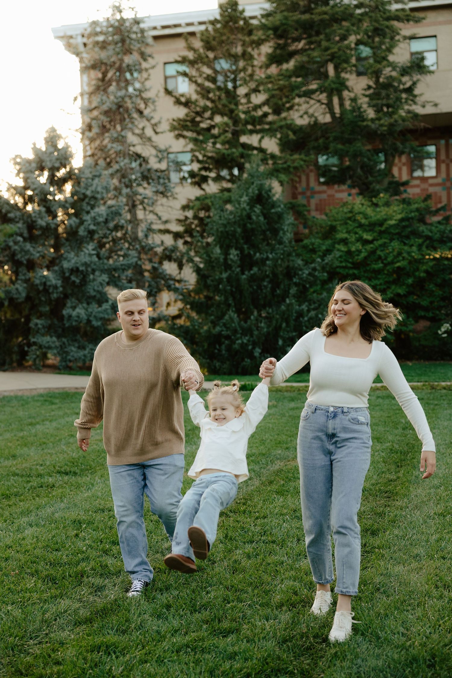 A couple swings their toddler during a sunset photoshoot in Lincoln, Nebraska.