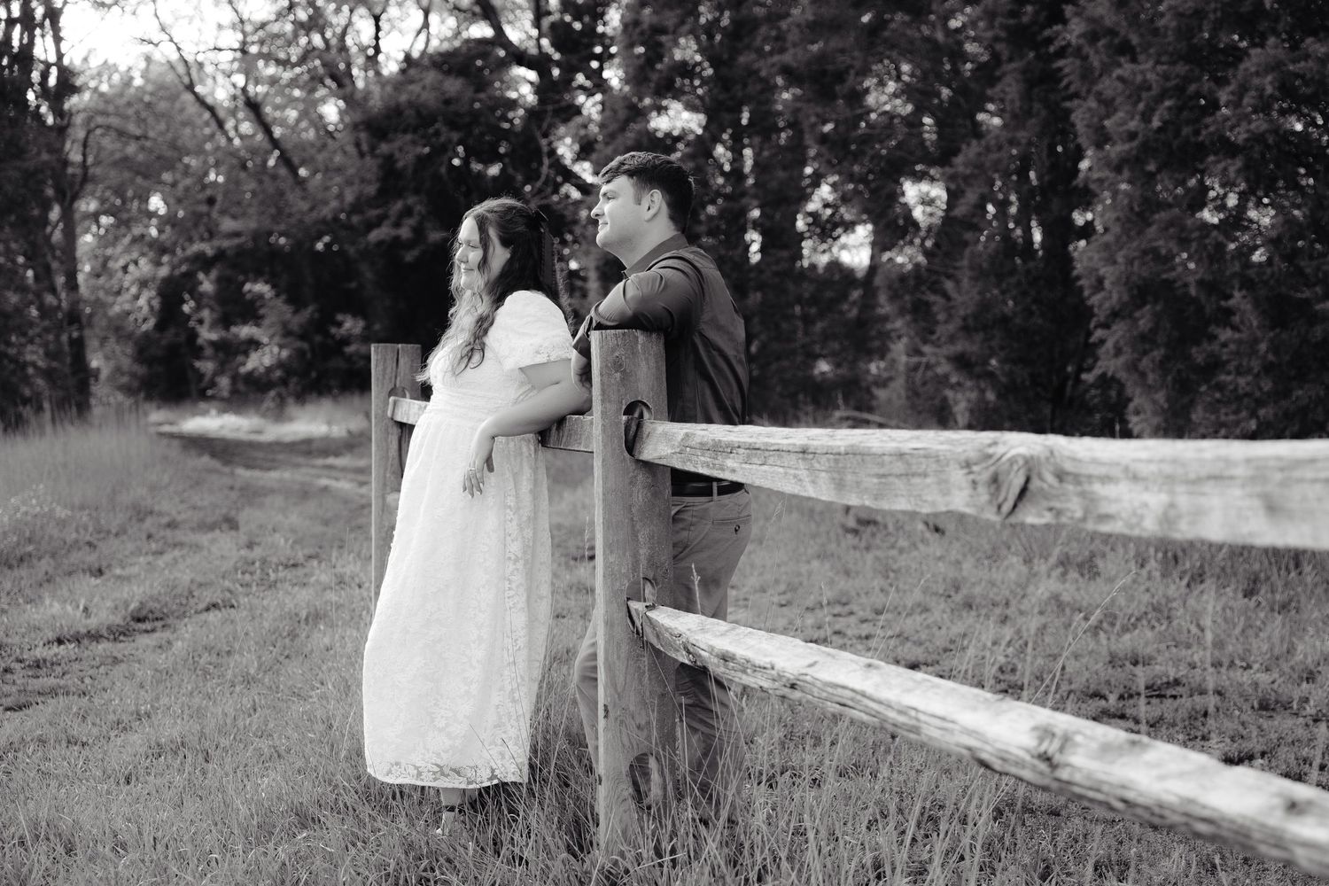 A couple embraces tenderly in an outdoor setting while wearing blue and white outfits in golden sunlight.