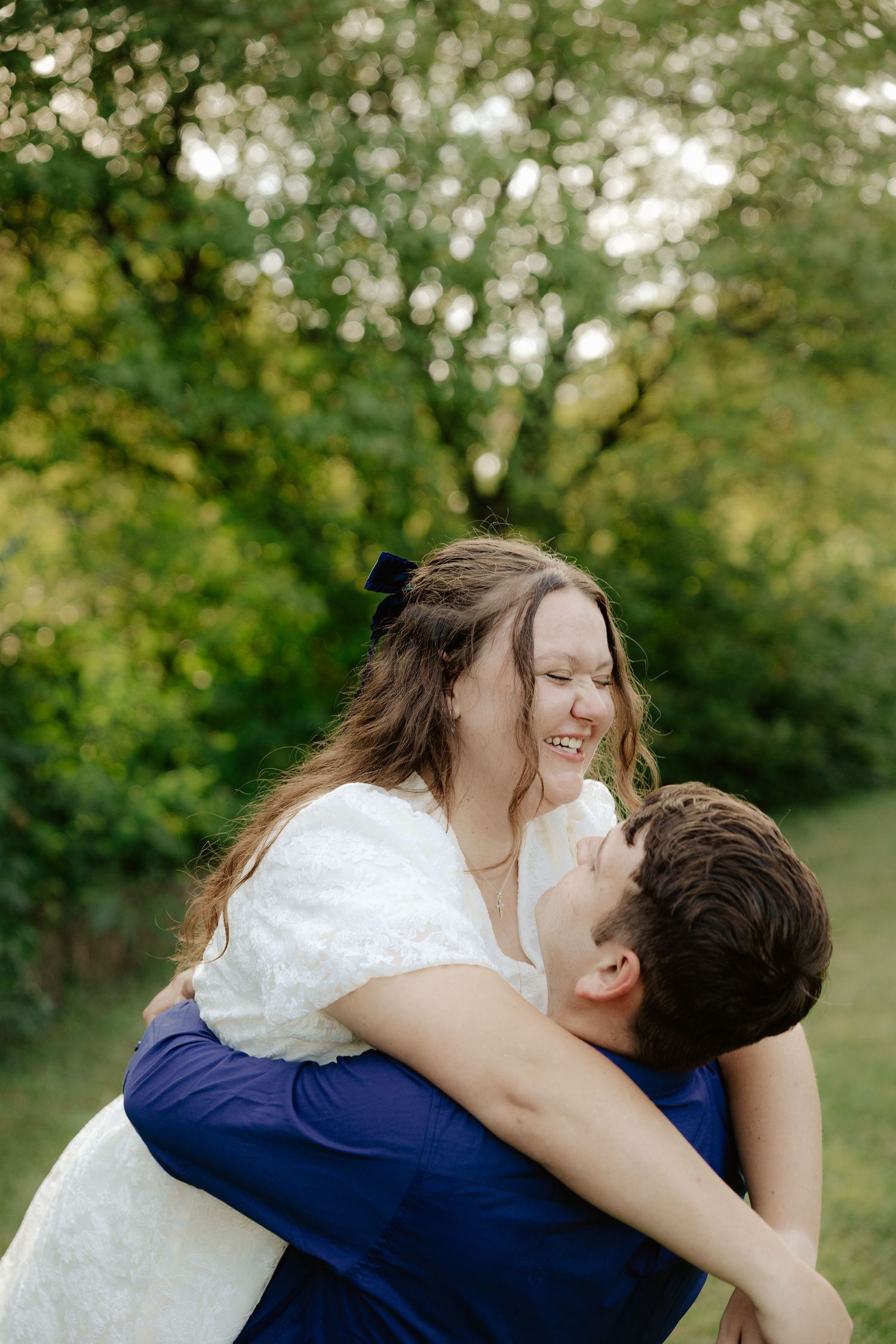 A couple walking hand in hand through lush green foliage on a summer afternoon.