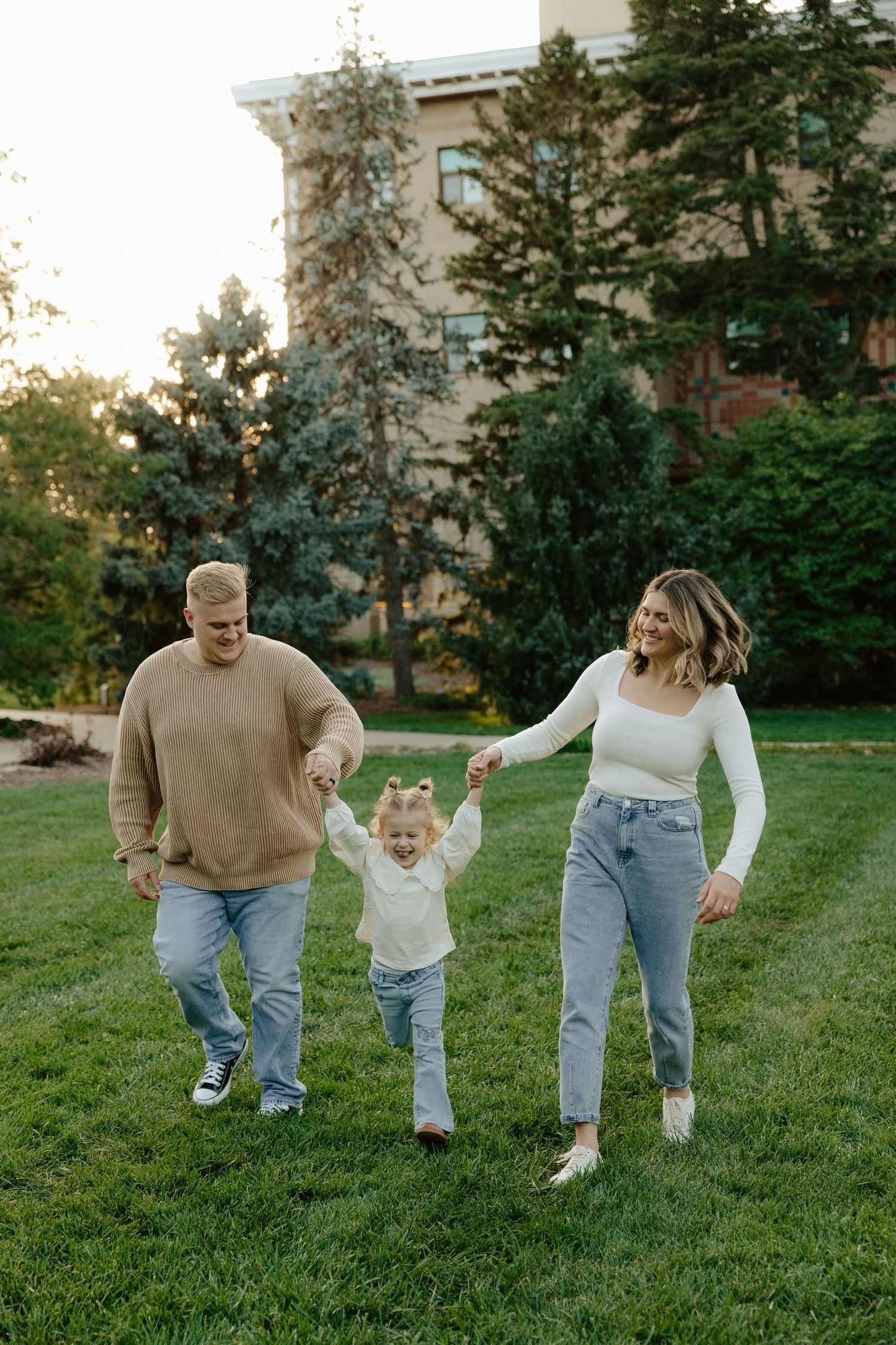 A couple swings their toddler during a sunset photoshoot in Lincoln, Nebraska.