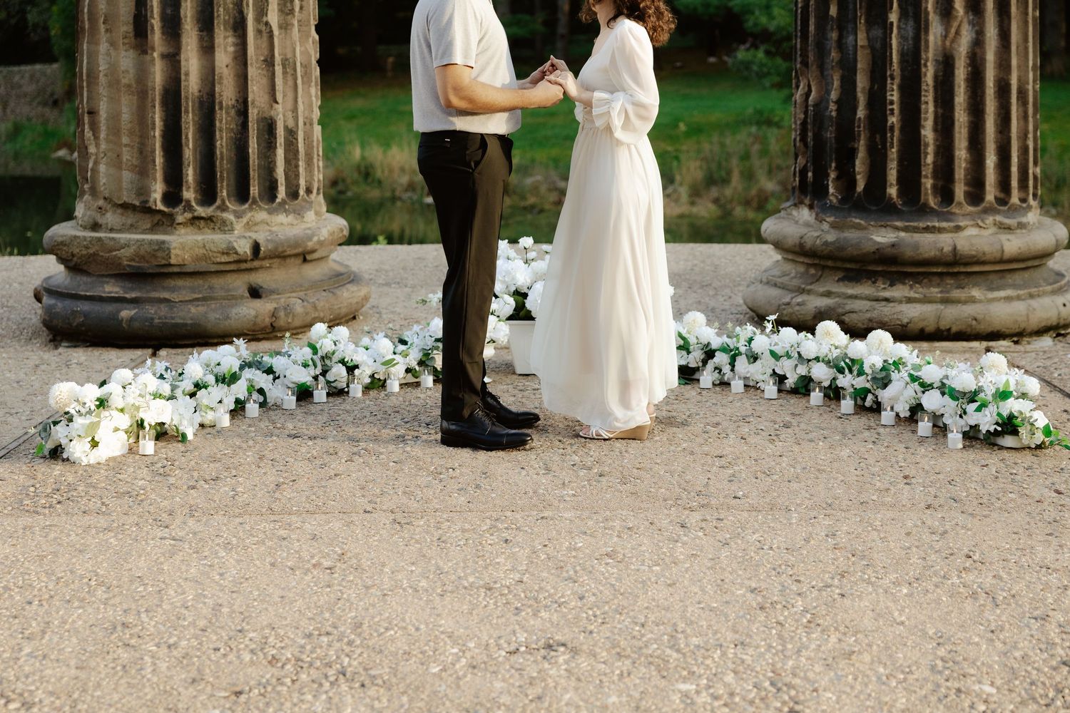 Couple shares romantic moment against stone pillars at sunset during outdoor wedding photoshoot.