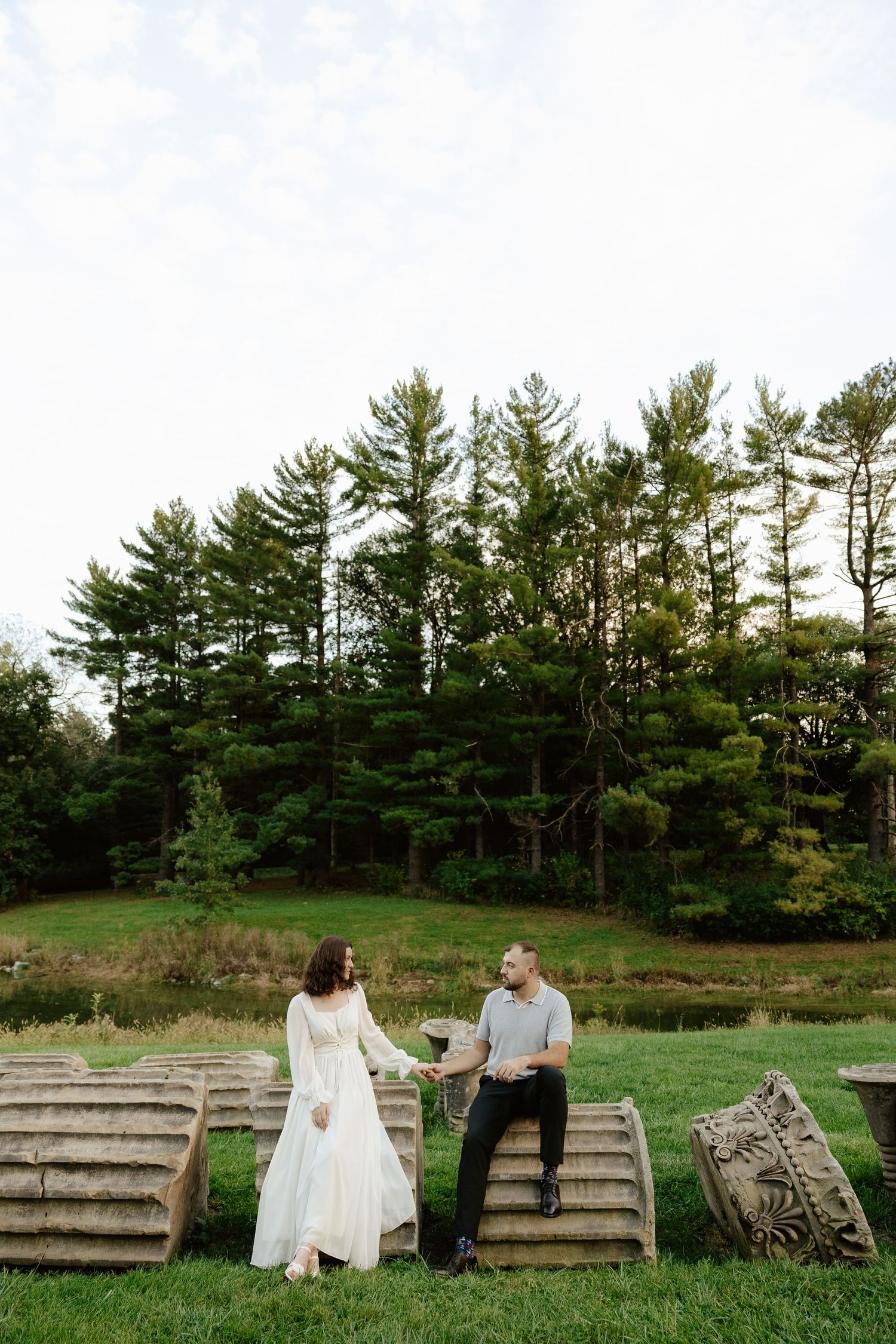 Couple shares romantic moment against stone pillars at sunset during outdoor wedding photoshoot.